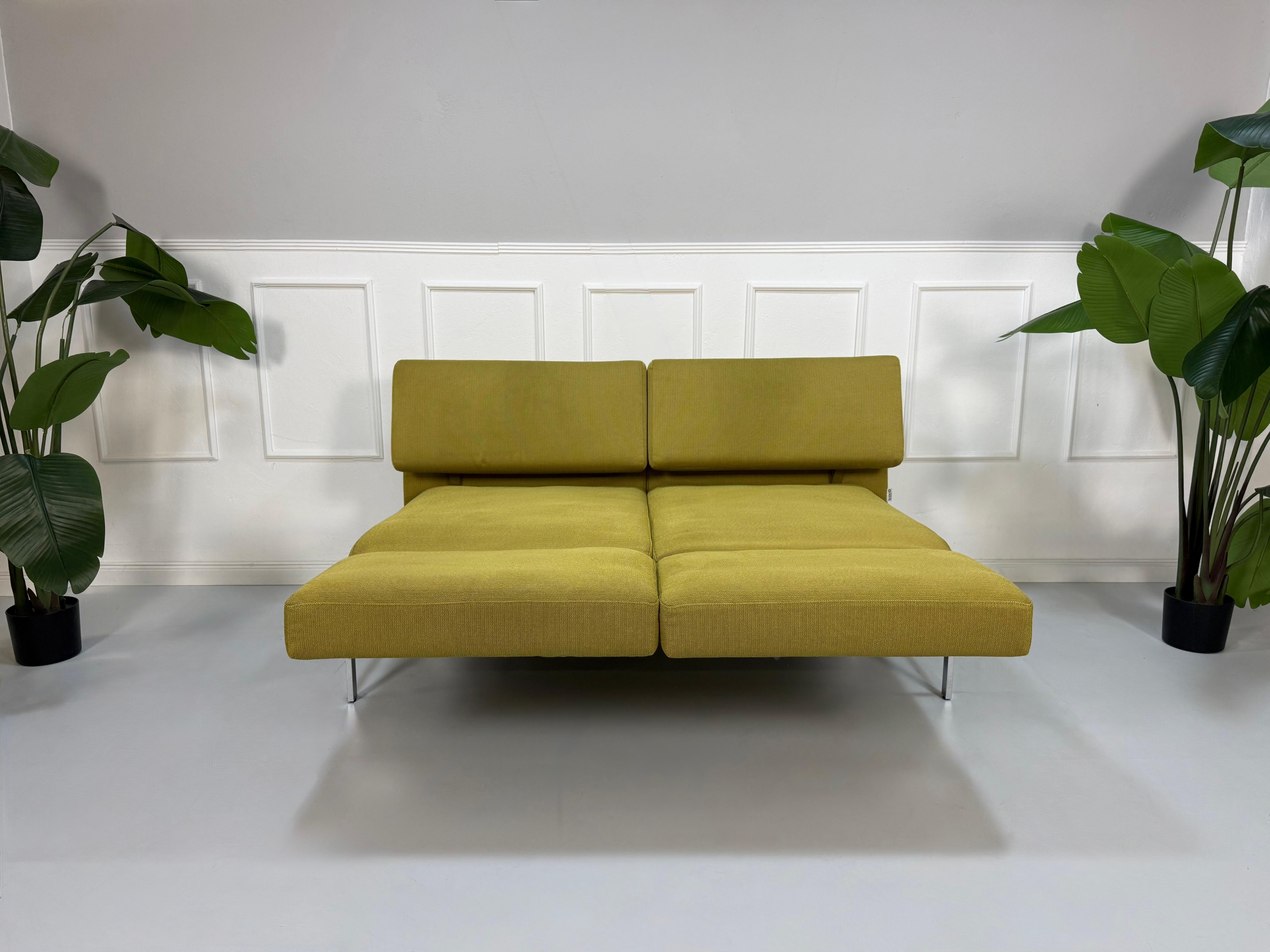 Gebrauchtes grünes Brühl Roro Soft Designer Stoff Sofa vor einer Wand, stilvoll und modern eingerichtet.