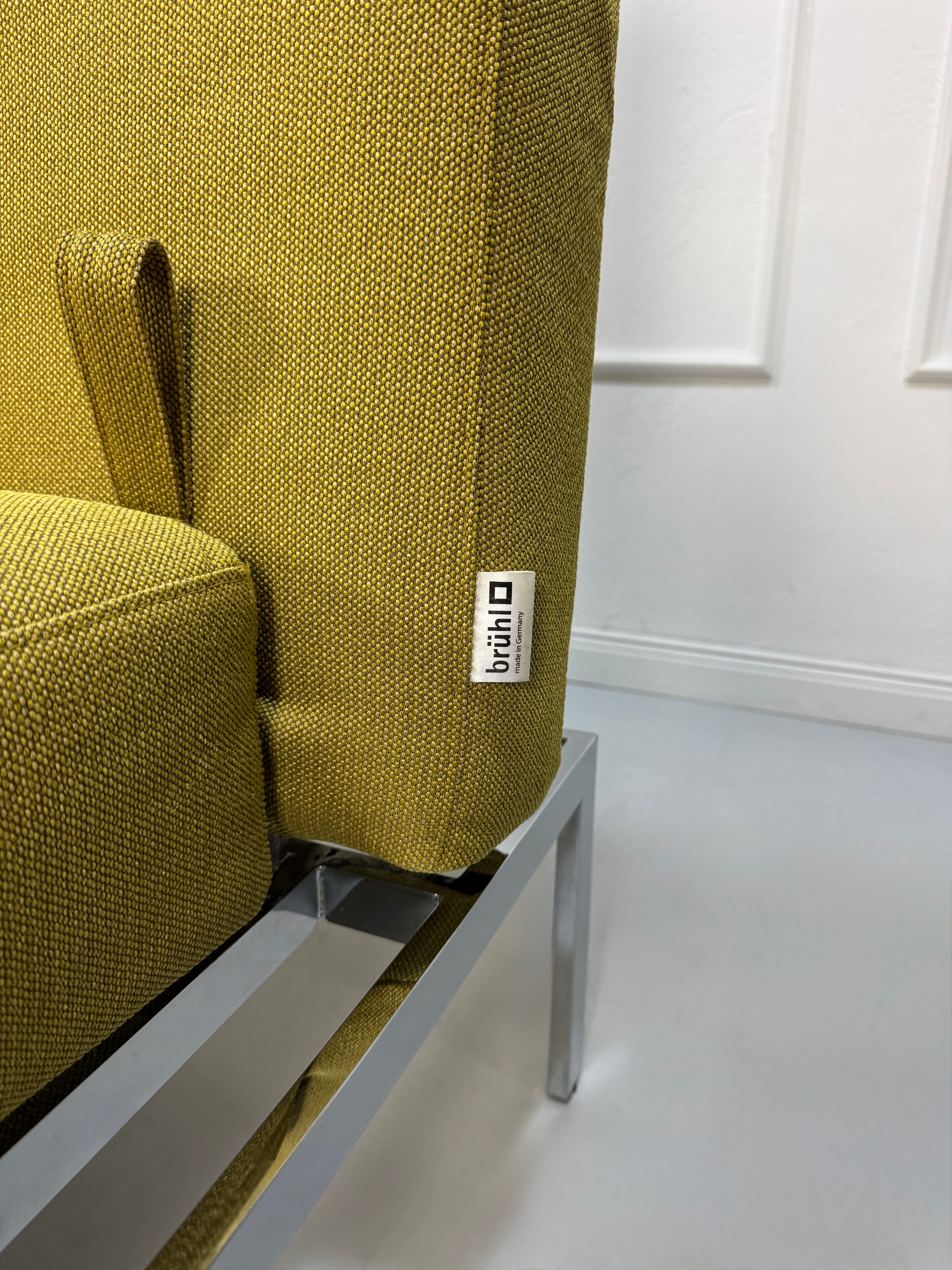 Gebrauchtes grünes Brühl Roro Soft Designer Stoff Sofa vor einer Wand, stilvoll und modern eingerichtet.