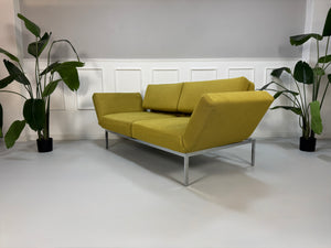 Gebrauchtes grünes Brühl Roro Soft Designer Stoff Sofa vor einer Wand, stilvoll und modern eingerichtet.
