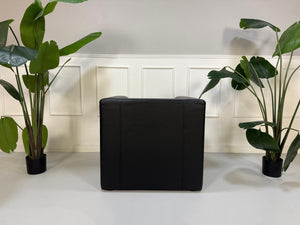 Gebrauchter schwarzer Brühl Visavis  Designer Leder Sessel vor einer Wand, stilvoll und modern eingerichtet.