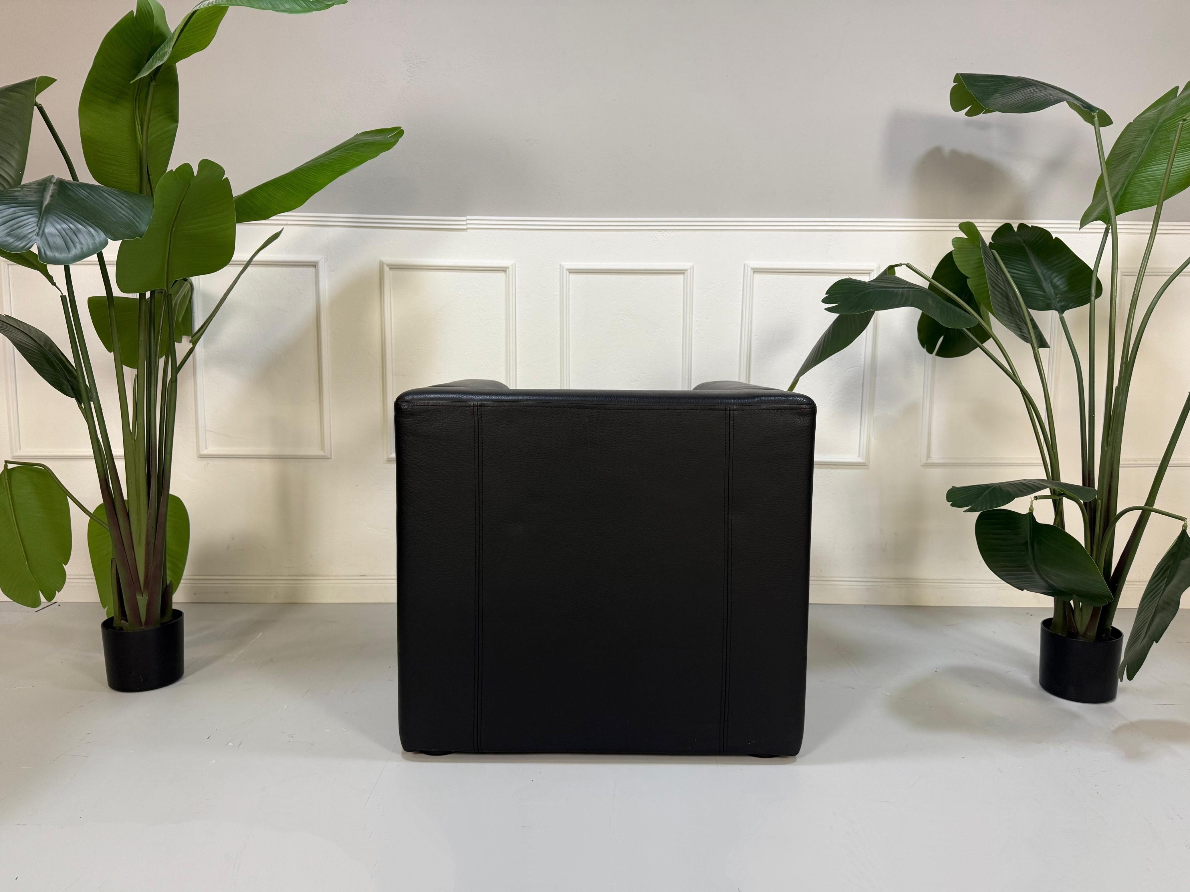 Gebrauchter schwarzer Brühl Visavis  Designer Leder Sessel vor einer Wand, stilvoll und modern eingerichtet.