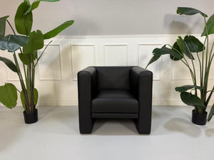 Gebrauchter schwarzer Brühl Visavis  Designer Leder Sessel vor einer Wand, stilvoll und modern eingerichtet.