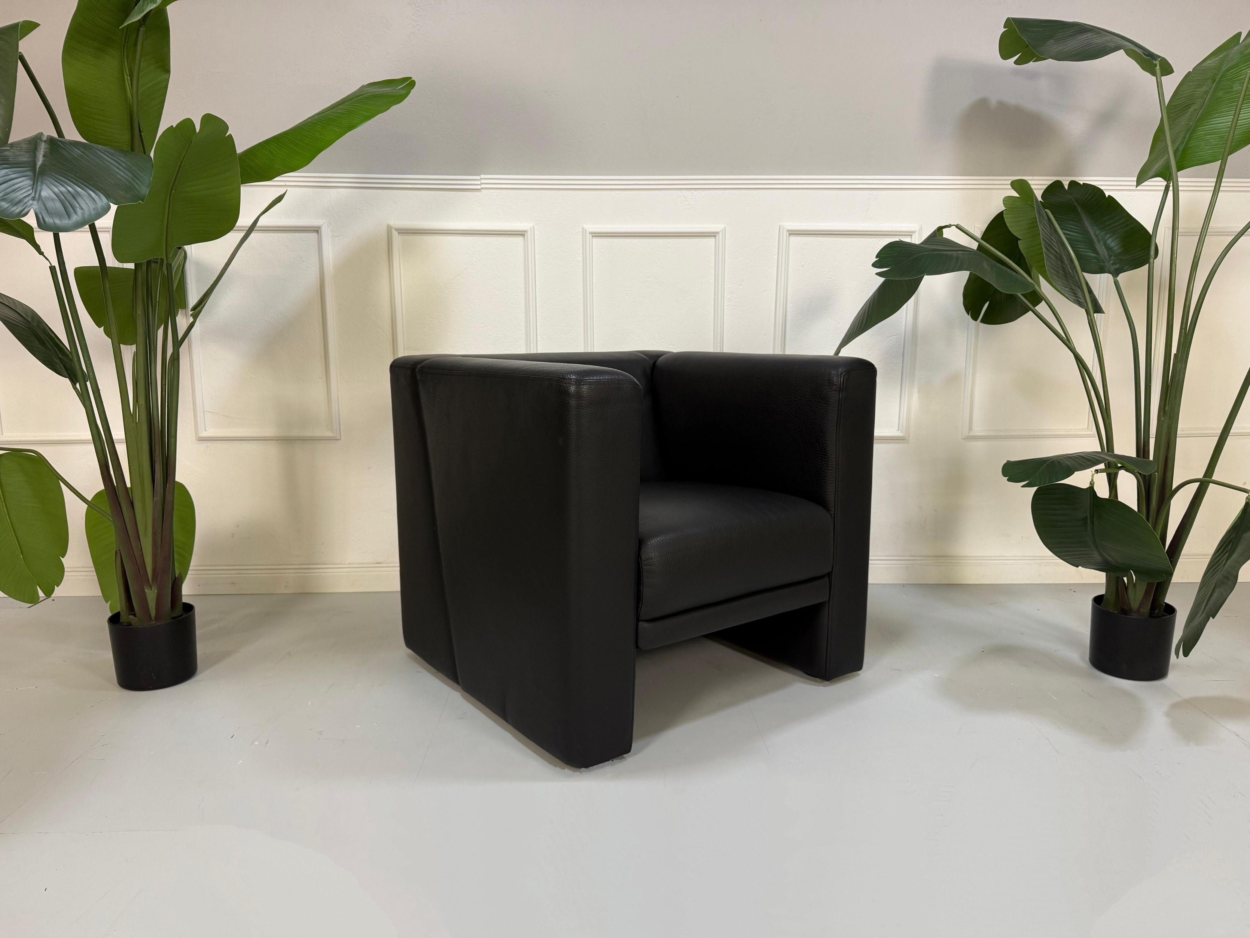 Gebrauchter schwarzer Brühl Visavis  Designer Leder Sessel vor einer Wand, stilvoll und modern eingerichtet.