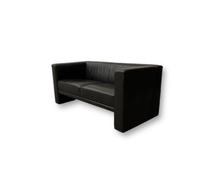 Gebrauchtes Brühl Visavis Leder Sofa in der Farbe Schwarz vor einer Wand, stilvoll und modern eingerichtet.