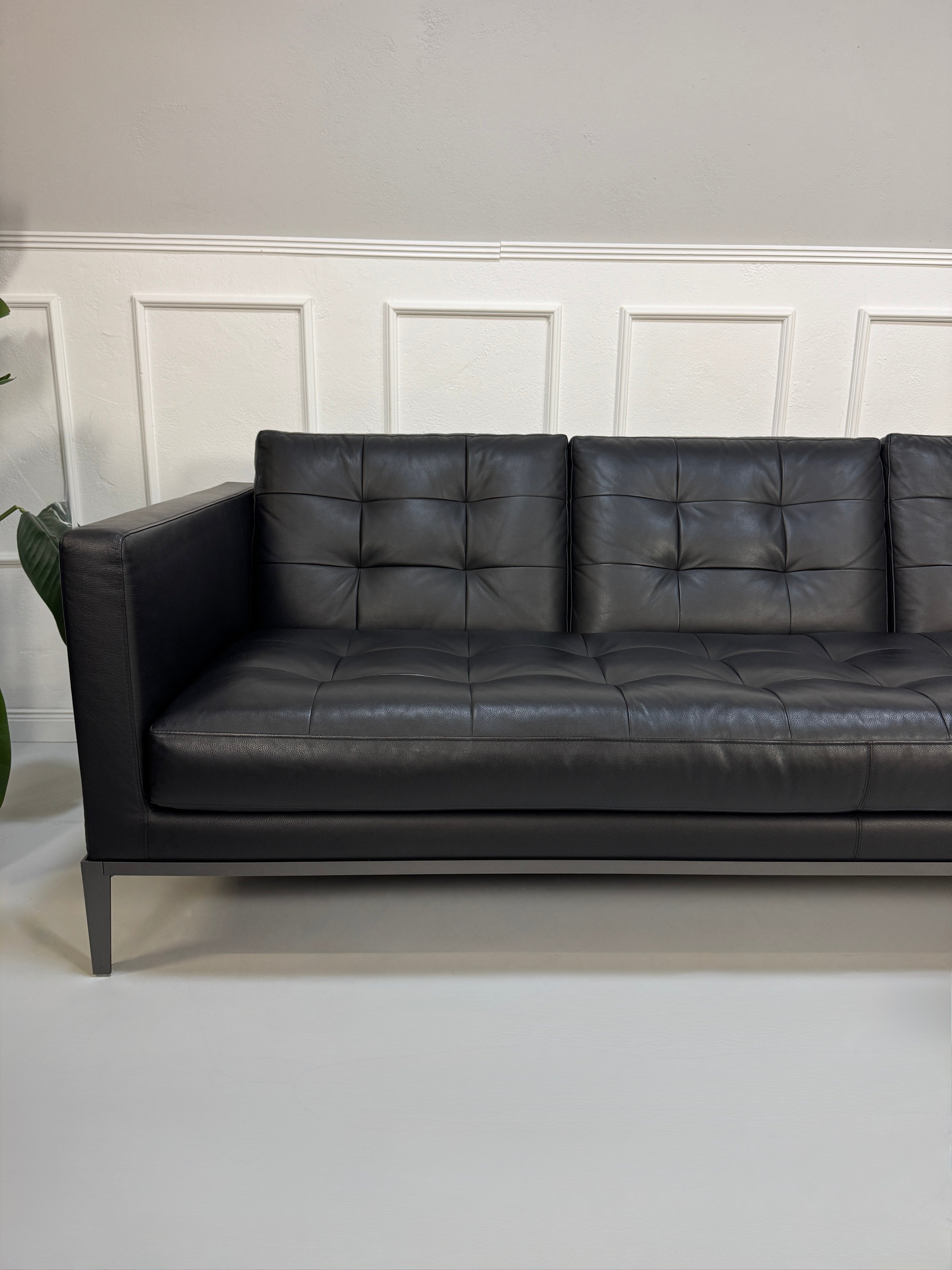 Gebrauchtes schwarzes B&B Italia AC Lounge Designer Leder Sofa vor einer Wand, stilvoll und modern eingerichtet.