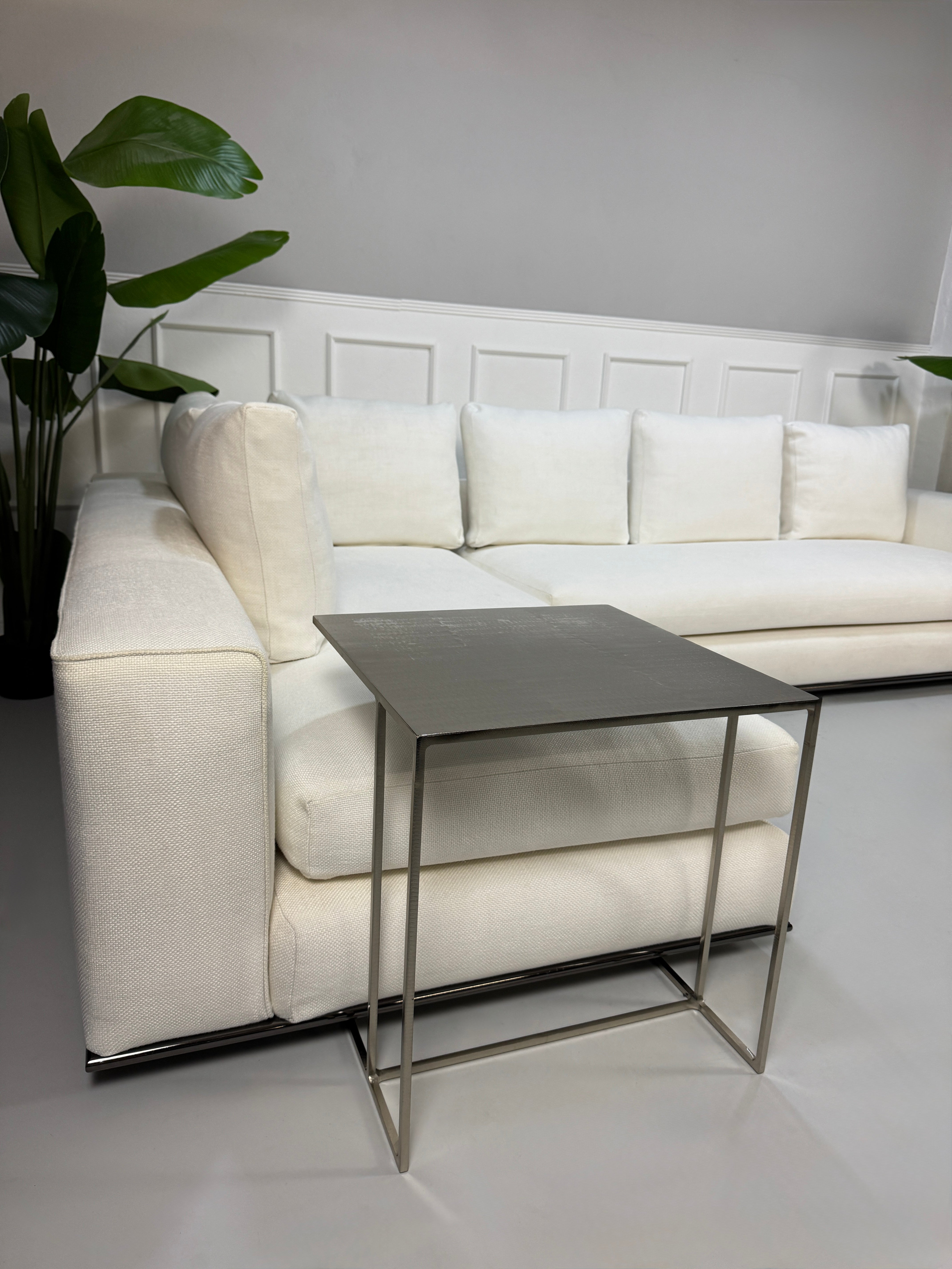 Gebrauchtes weißes Stoff Sofa Minotti Hamilton vor einer modernen Wand.