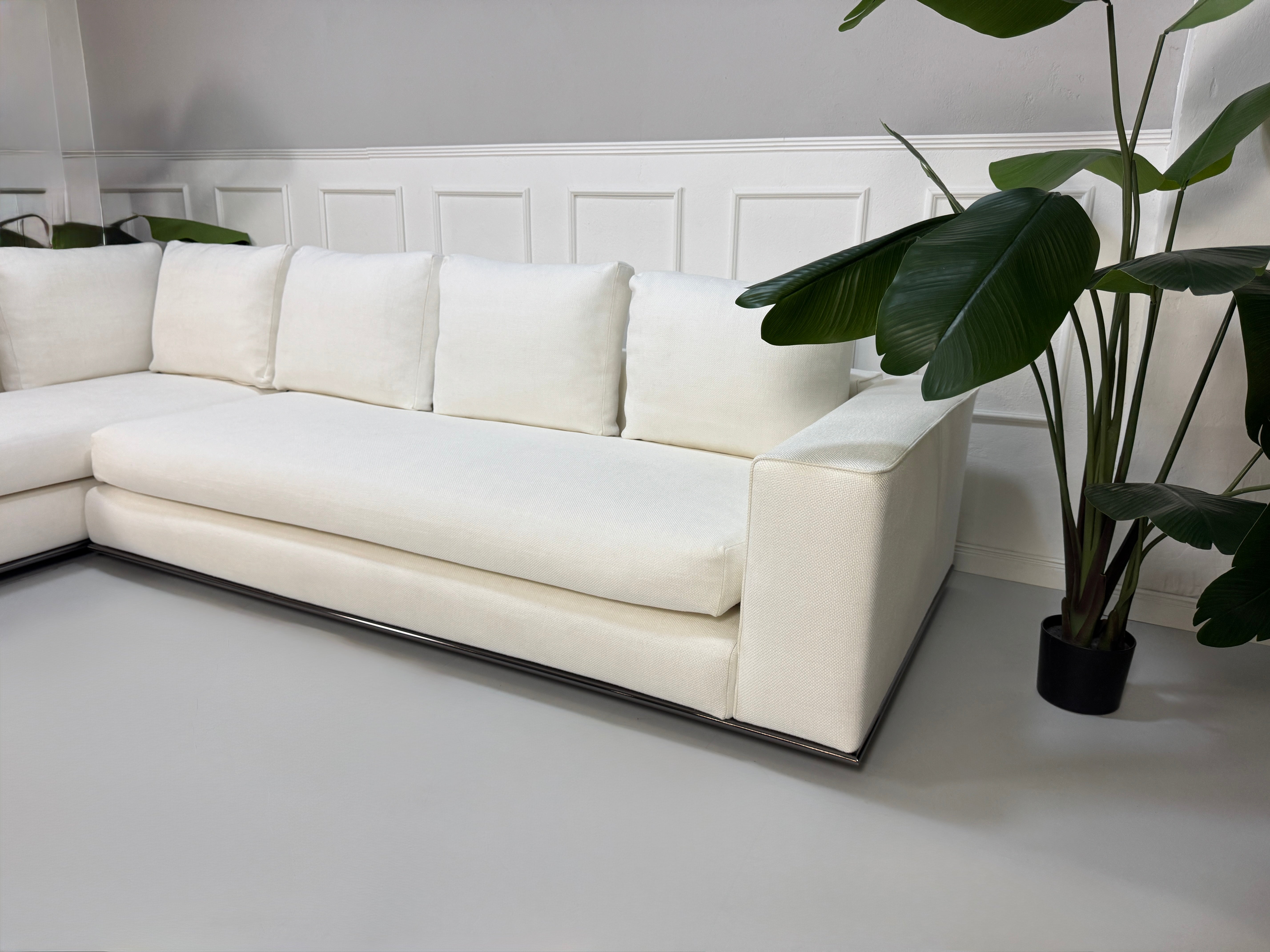 Gebrauchtes weißes Stoff Sofa Minotti Hamilton vor einer modernen Wand.