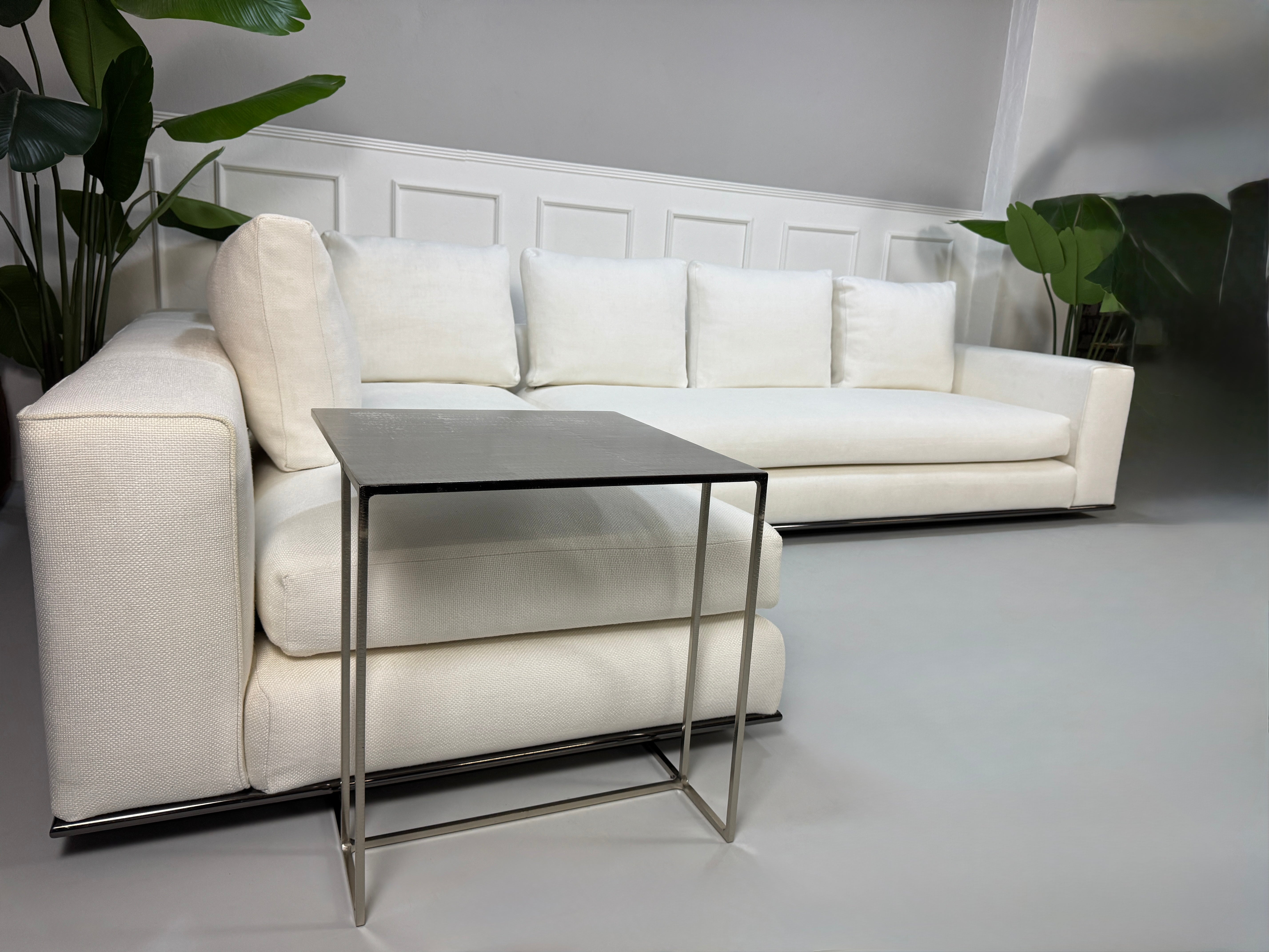 Gebrauchtes weißes Stoff Sofa Minotti Hamilton vor einer modernen Wand.