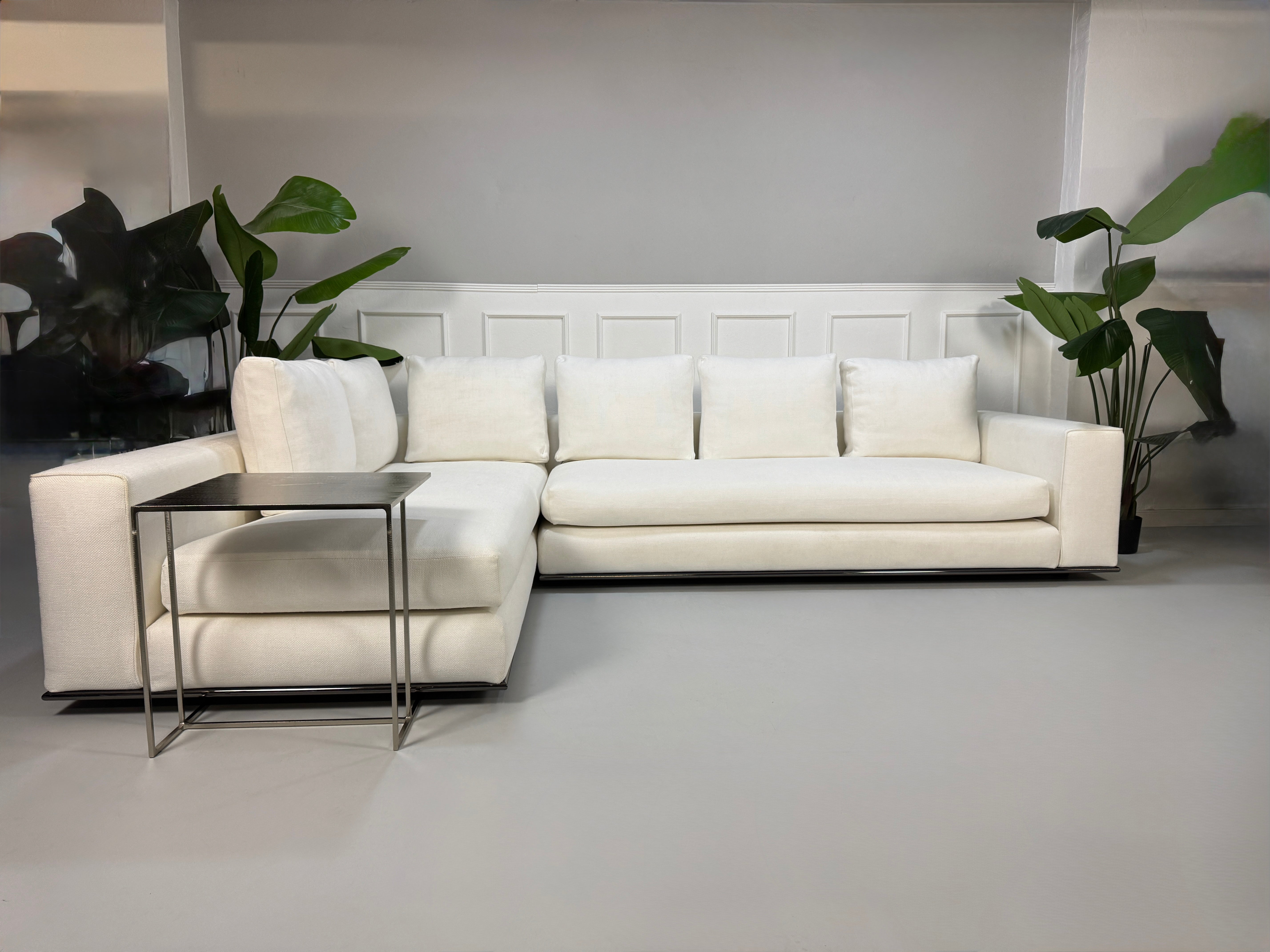 Gebrauchtes weißes Stoff Sofa Minotti Hamilton vor einer modernen Wand.