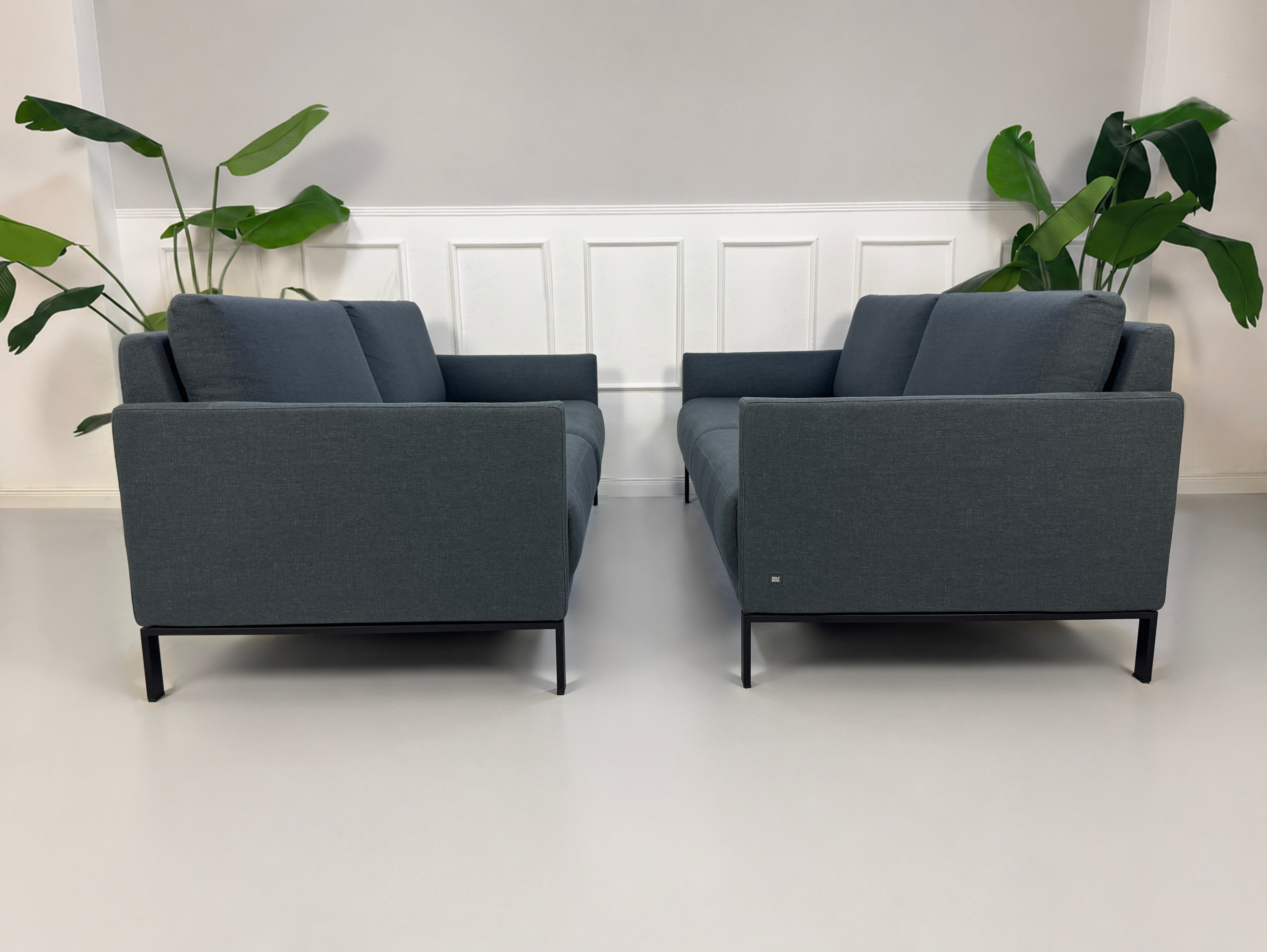 Gebrauchte graue Rolf Benz Cara Designer Stoff Sofa Garnitur vor einer Wand, stilvoll und modern eingerichtet.