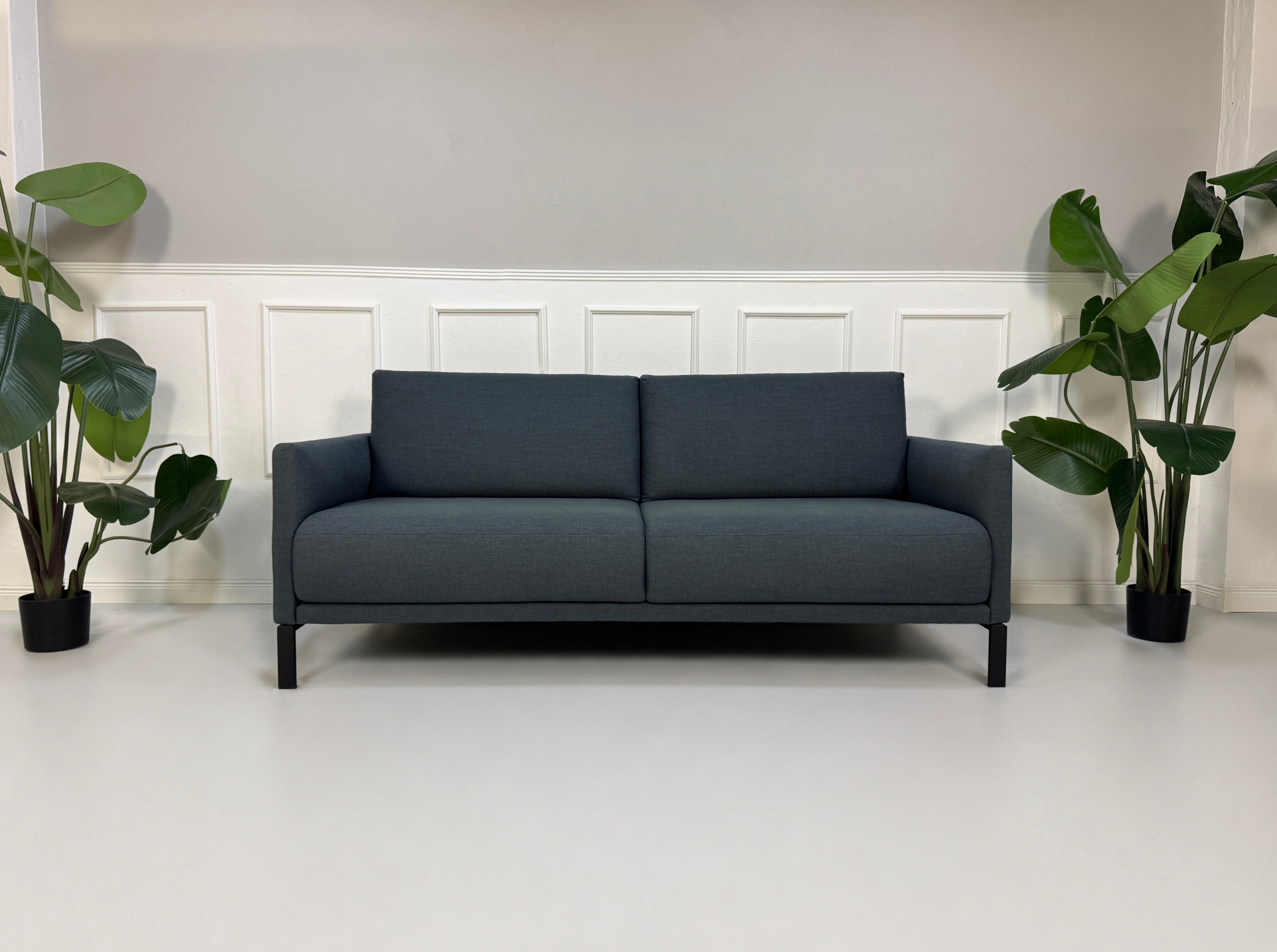 Gebrauchte graue Rolf Benz Cara Designer Stoff Sofa Garnitur vor einer Wand, stilvoll und modern eingerichtet.