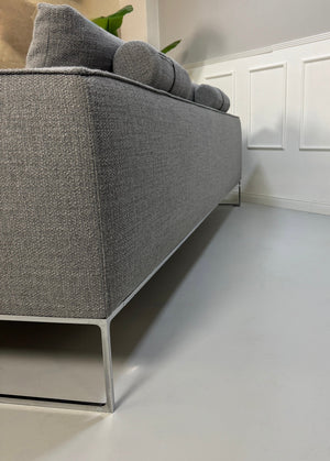 Erneuertes graues COR Mell Designer Stoff Sofa vor einer Wand, stilvoll und modern eingerichtet.