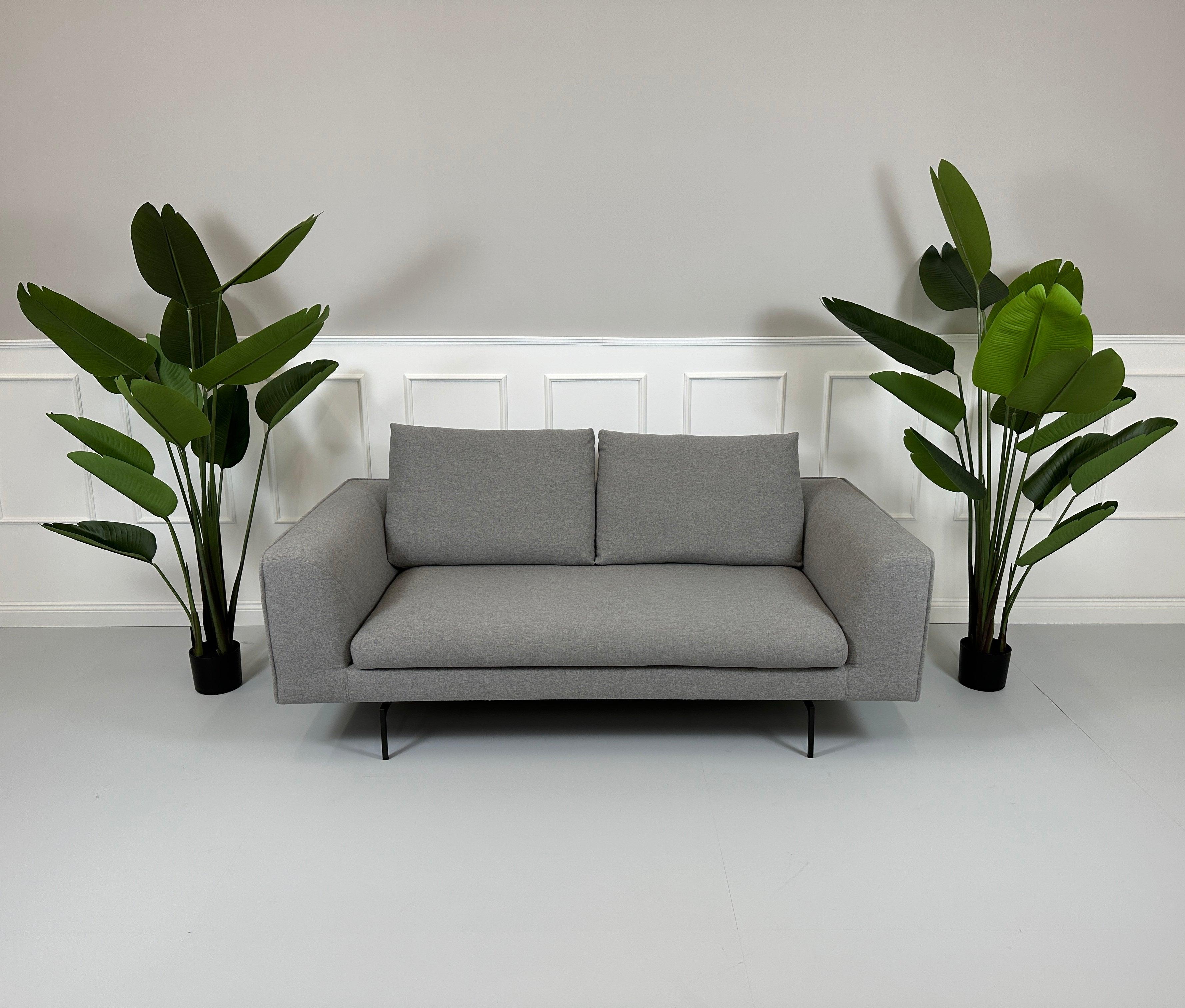 Gebrauchtes COR Mell Stoff Sofa in der Farbe Grau vor einer Wand, stilvoll und modern eingerichtet.