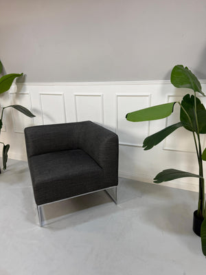 Gebrauchtes graues COR Mell Designer Stoff Sofa vor einer Wand, stilvoll und modern eingerichtet.