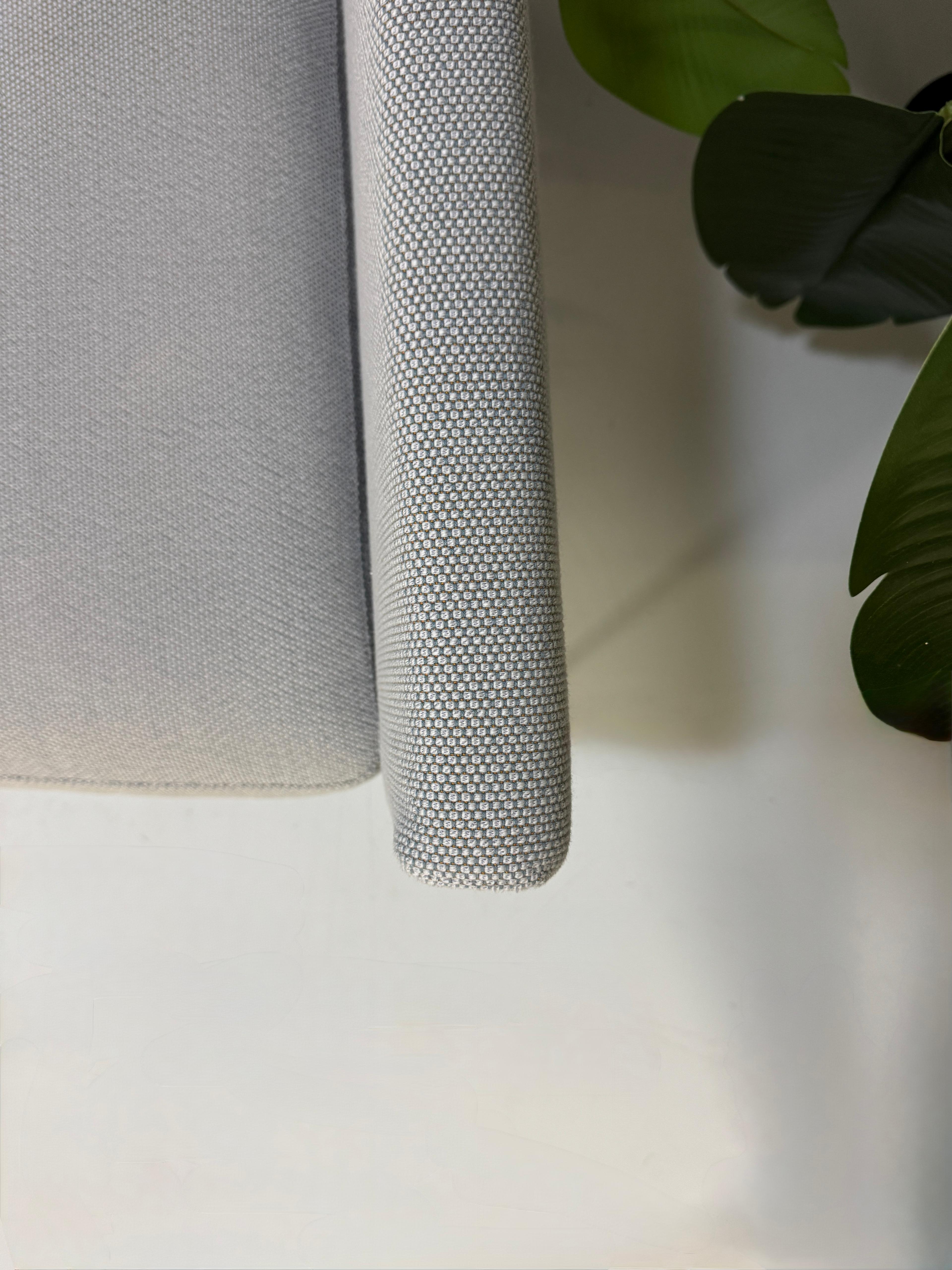 Gebrauchtes graues COR Pilotis Designer Stoff Sofa vor einer Wand, stilvoll und modern eingerichtet.