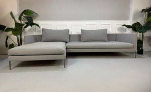 Gebrauchtes graues COR Pilotis Designer Stoff Sofa vor einer Wand, stilvoll und modern eingerichtet.