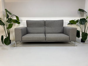 Gebrauchtes graues Cassina Moov Designer Stoff Sofa vor einer Wand, stilvoll und modern eingerichtet.