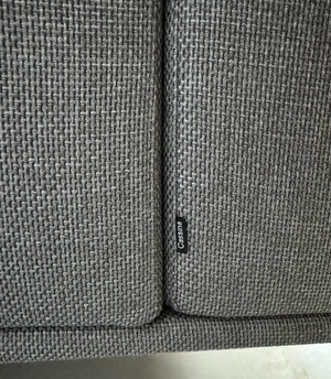 Gebrauchtes graues Cassina Moov Designer Stoff Sofa vor einer Wand, stilvoll und modern eingerichtet.
