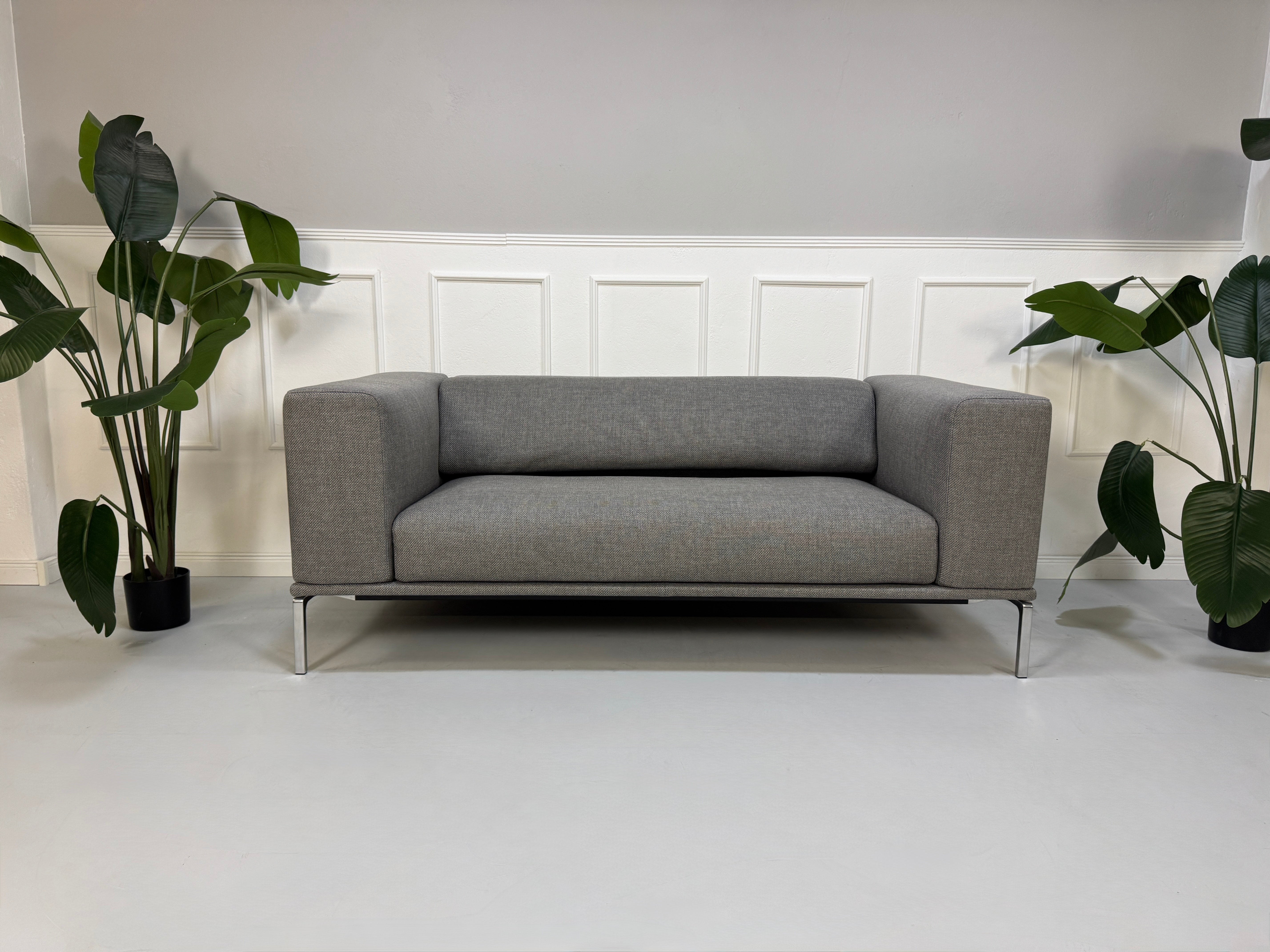 Gebrauchtes graues Cassina Moov Designer Stoff Sofa vor einer Wand, stilvoll und modern eingerichtet.