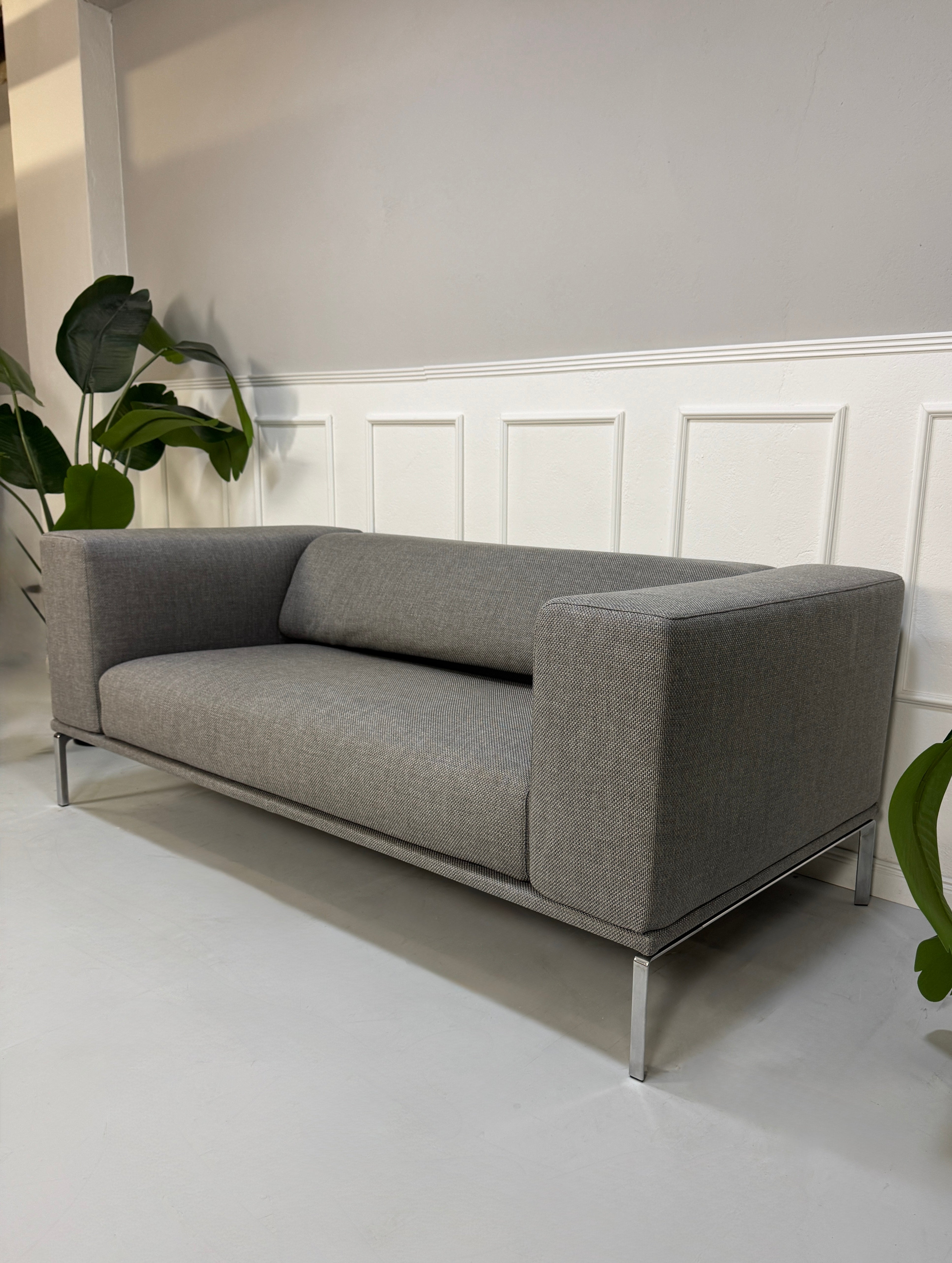 Gebrauchtes graues Cassina Moov Designer Stoff Sofa vor einer Wand, stilvoll und modern eingerichtet.