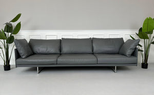 Gebrauchtes graues Cassina Toot Designer Leder Sofa vor einer Wand, stilvoll und modern eingerichtet.