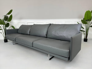 Gebrauchtes graues Cassina Toot Designer Leder Sofa vor einer Wand, stilvoll und modern eingerichtet.