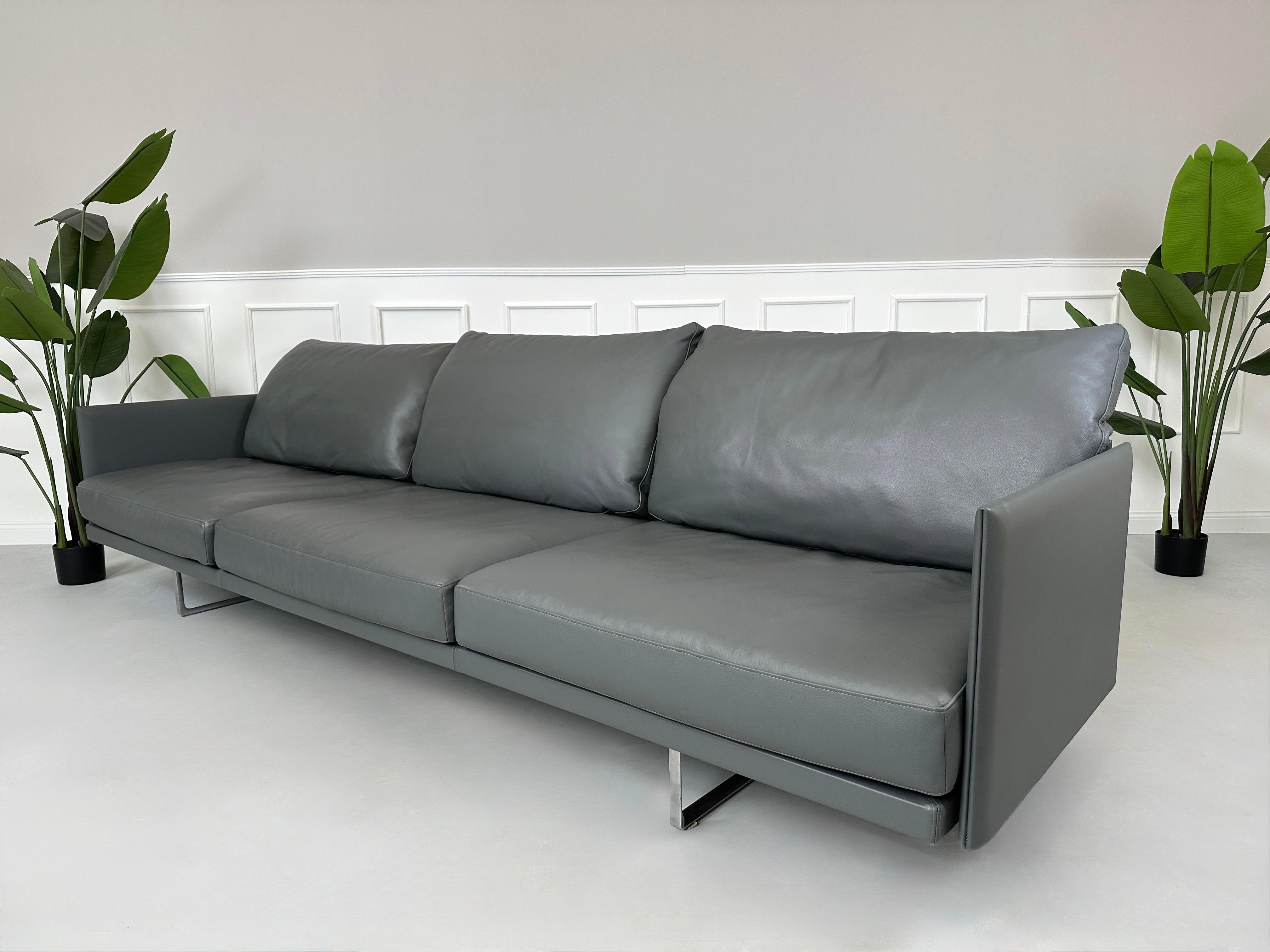 Gebrauchtes graues Cassina Toot Designer Leder Sofa vor einer Wand, stilvoll und modern eingerichtet.