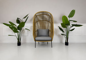 Gebrauchter outdoor DEDON Rilly Cocoon Garten Stuhl vor einer Wand, stilvoll und modern eingerichtet.