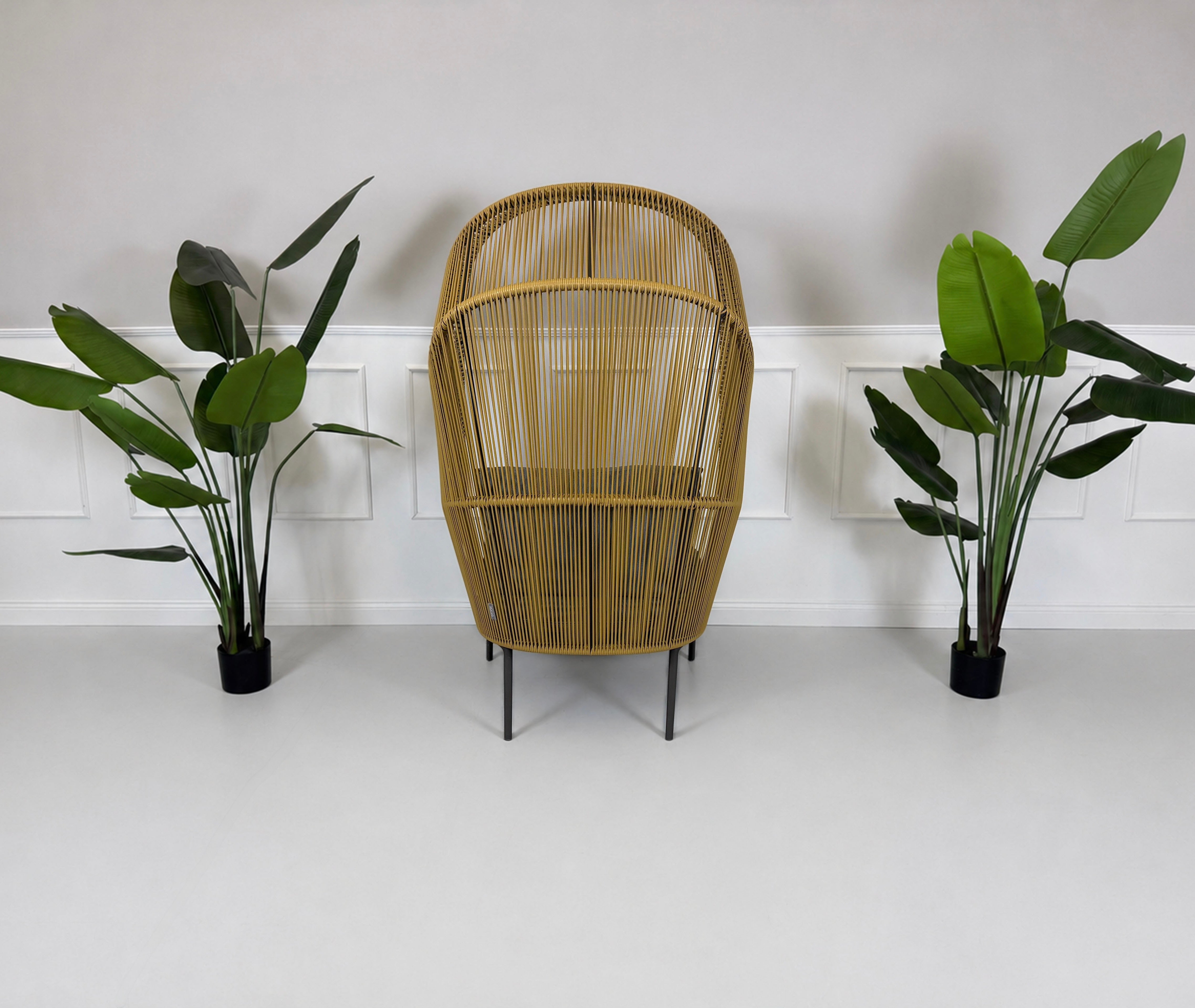 Gebrauchter outdoor DEDON Rilly Cocoon Garten Stuhl vor einer Wand, stilvoll und modern eingerichtet.