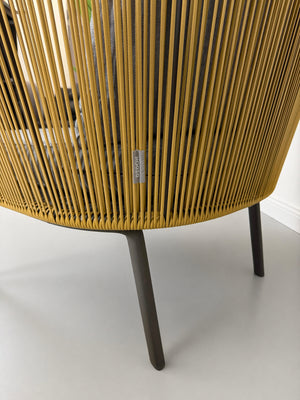 Gebrauchter outdoor DEDON Rilly Cocoon Garten Stuhl vor einer Wand, stilvoll und modern eingerichtet.