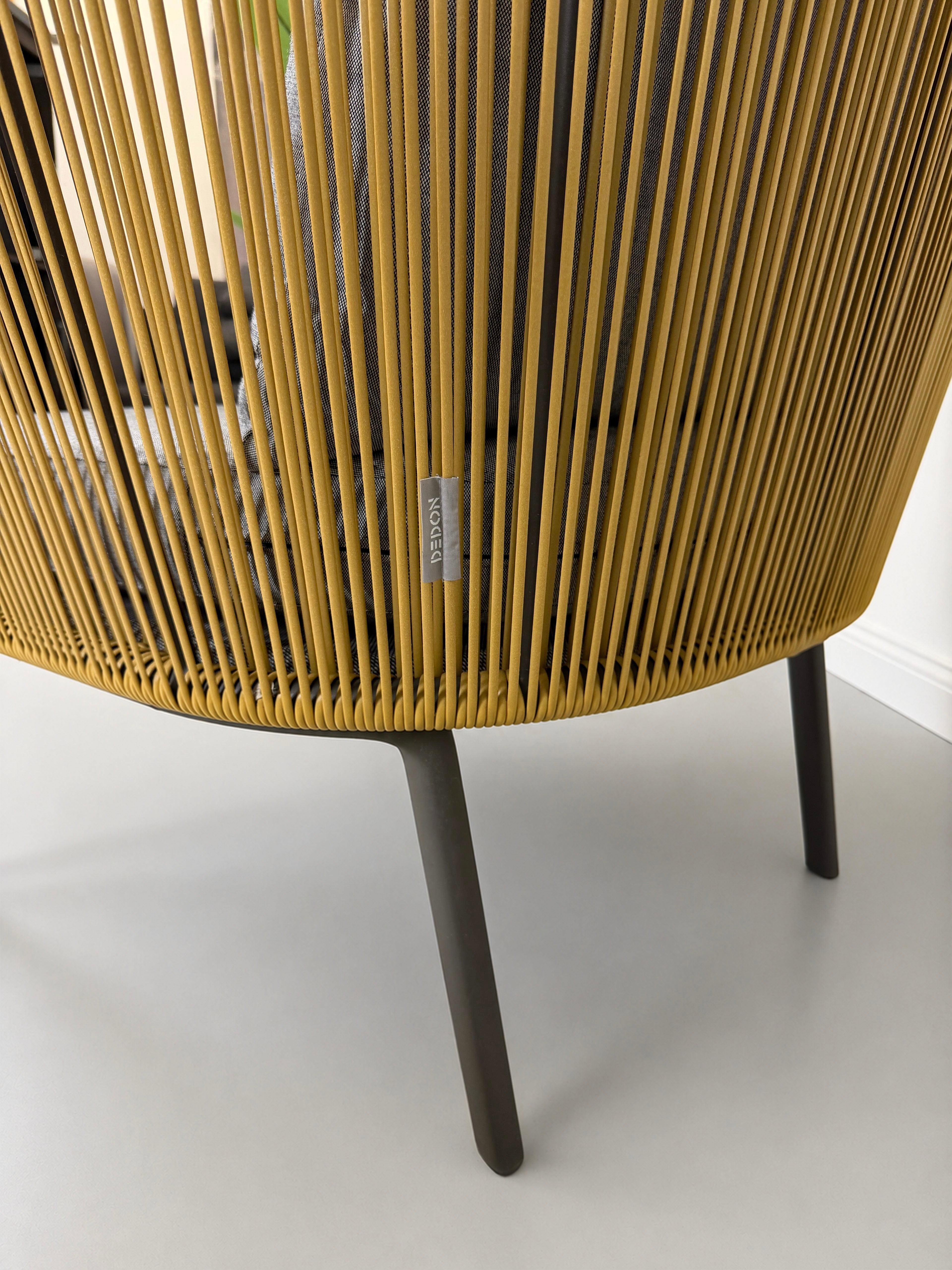 Gebrauchter outdoor DEDON Rilly Cocoon Garten Stuhl vor einer Wand, stilvoll und modern eingerichtet.