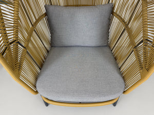 Gebrauchter outdoor DEDON Rilly Cocoon Garten Stuhl vor einer Wand, stilvoll und modern eingerichtet.