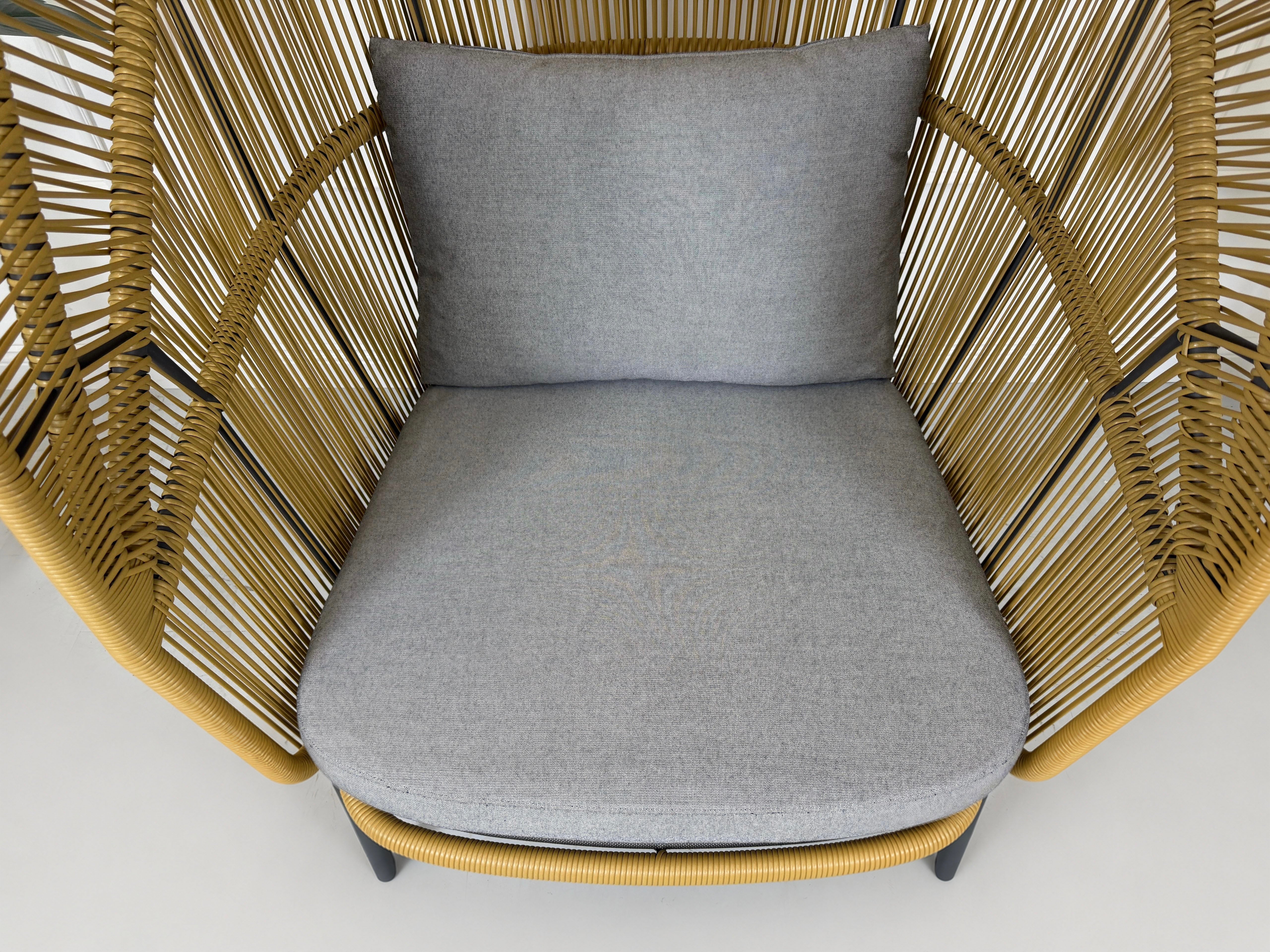 Gebrauchter outdoor DEDON Rilly Cocoon Garten Stuhl vor einer Wand, stilvoll und modern eingerichtet.