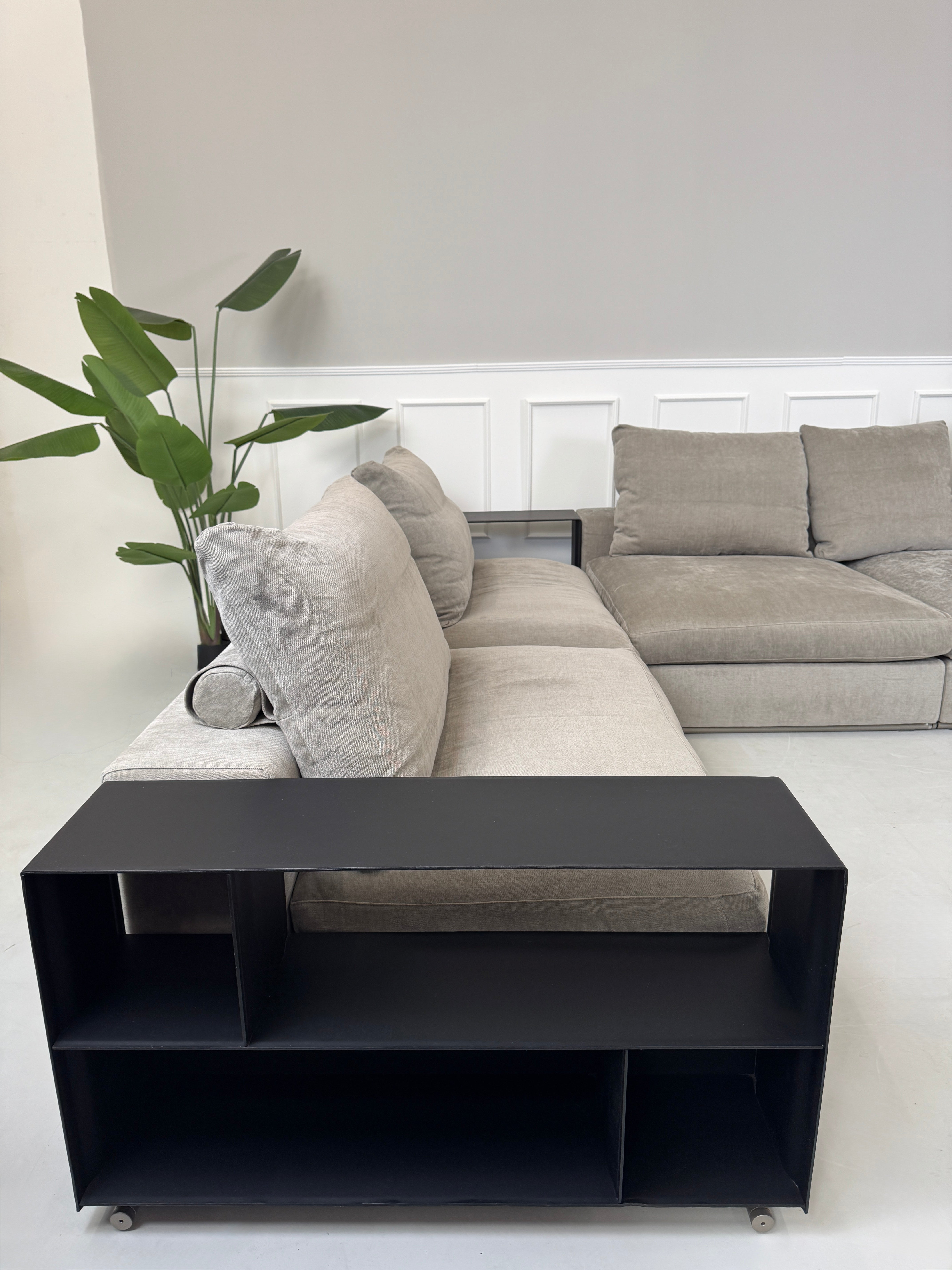 Gebrauchtes graues Flexform Groundpiece Designer Stoff Sofa vor einer Wand, stilvoll und modern eingerichtet.