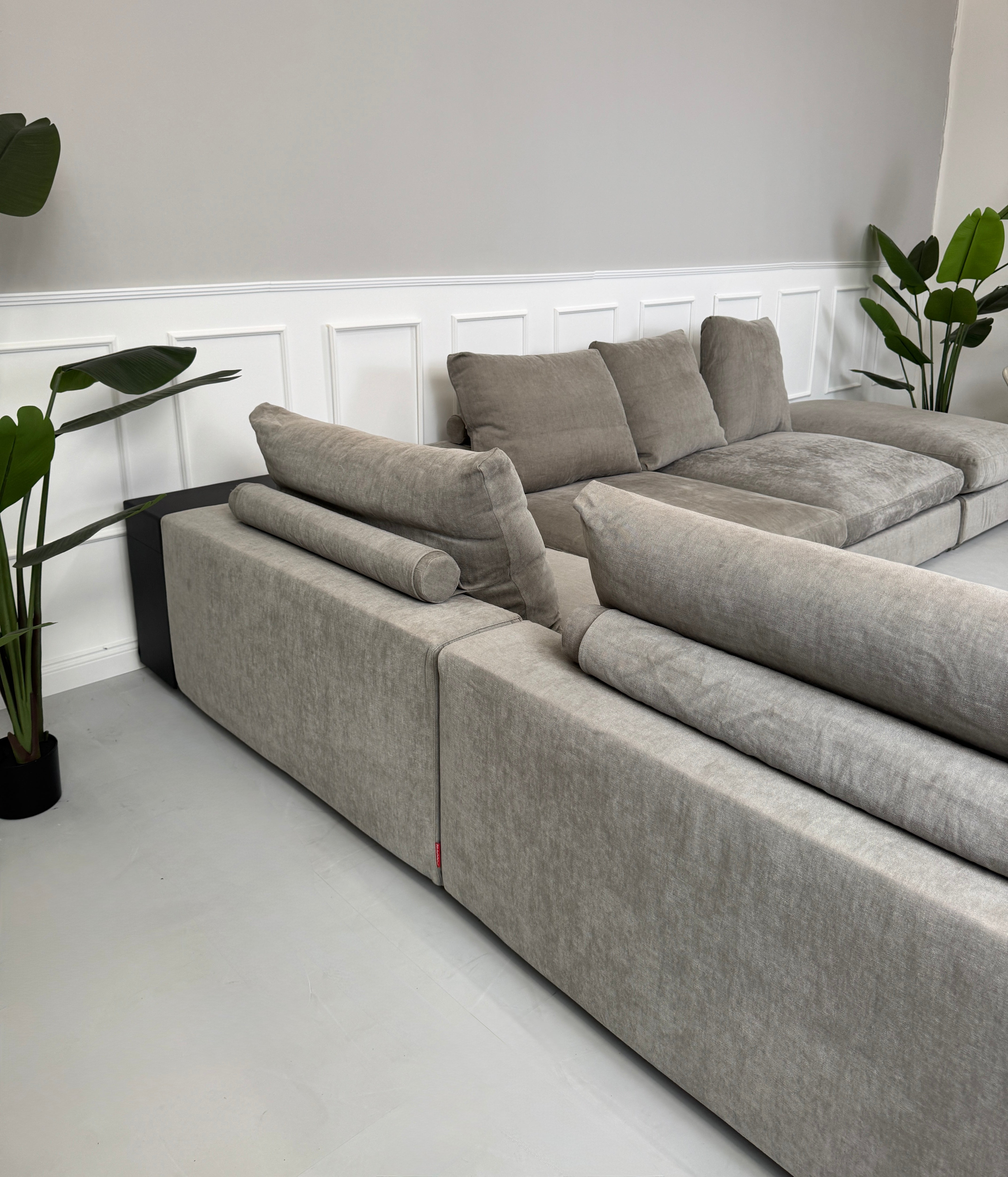 Gebrauchtes graues Flexform Groundpiece Designer Stoff Sofa vor einer Wand, stilvoll und modern eingerichtet.