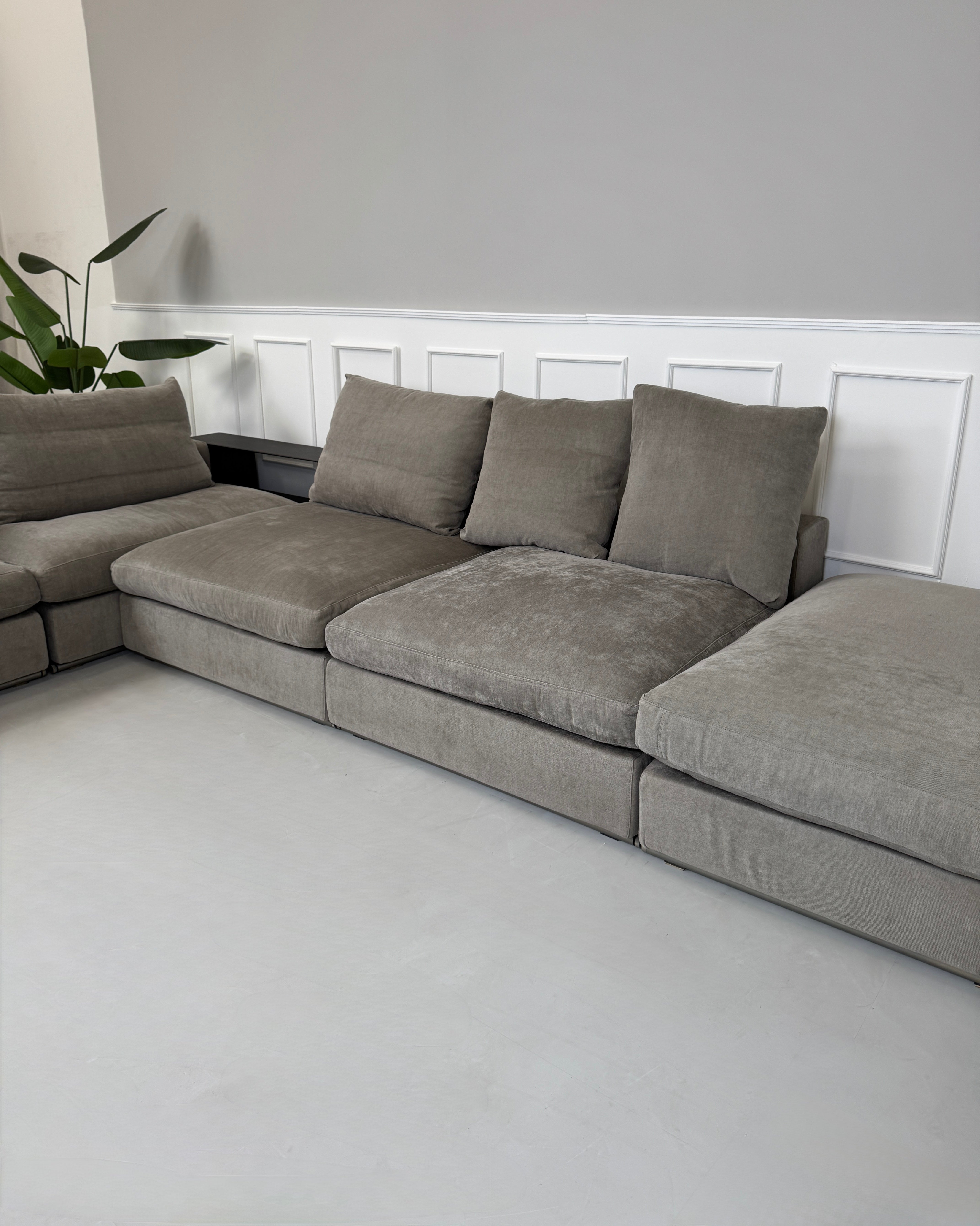 Gebrauchtes graues Flexform Groundpiece Designer Stoff Sofa vor einer Wand, stilvoll und modern eingerichtet.