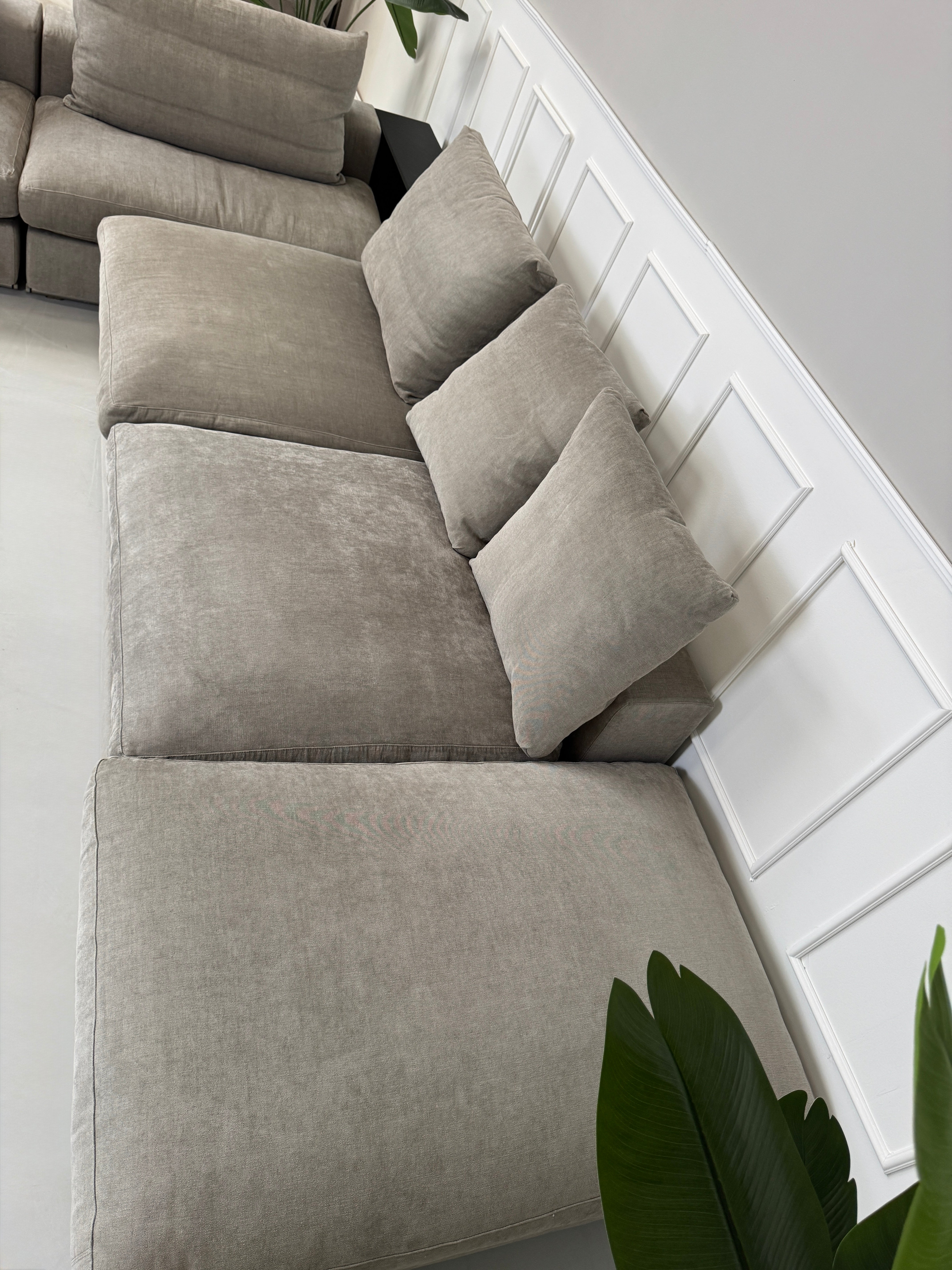 Gebrauchtes graues Flexform Groundpiece Designer Stoff Sofa vor einer Wand, stilvoll und modern eingerichtet.