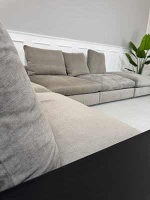 Gebrauchtes graues Flexform Groundpiece Designer Stoff Sofa vor einer Wand, stilvoll und modern eingerichtet.