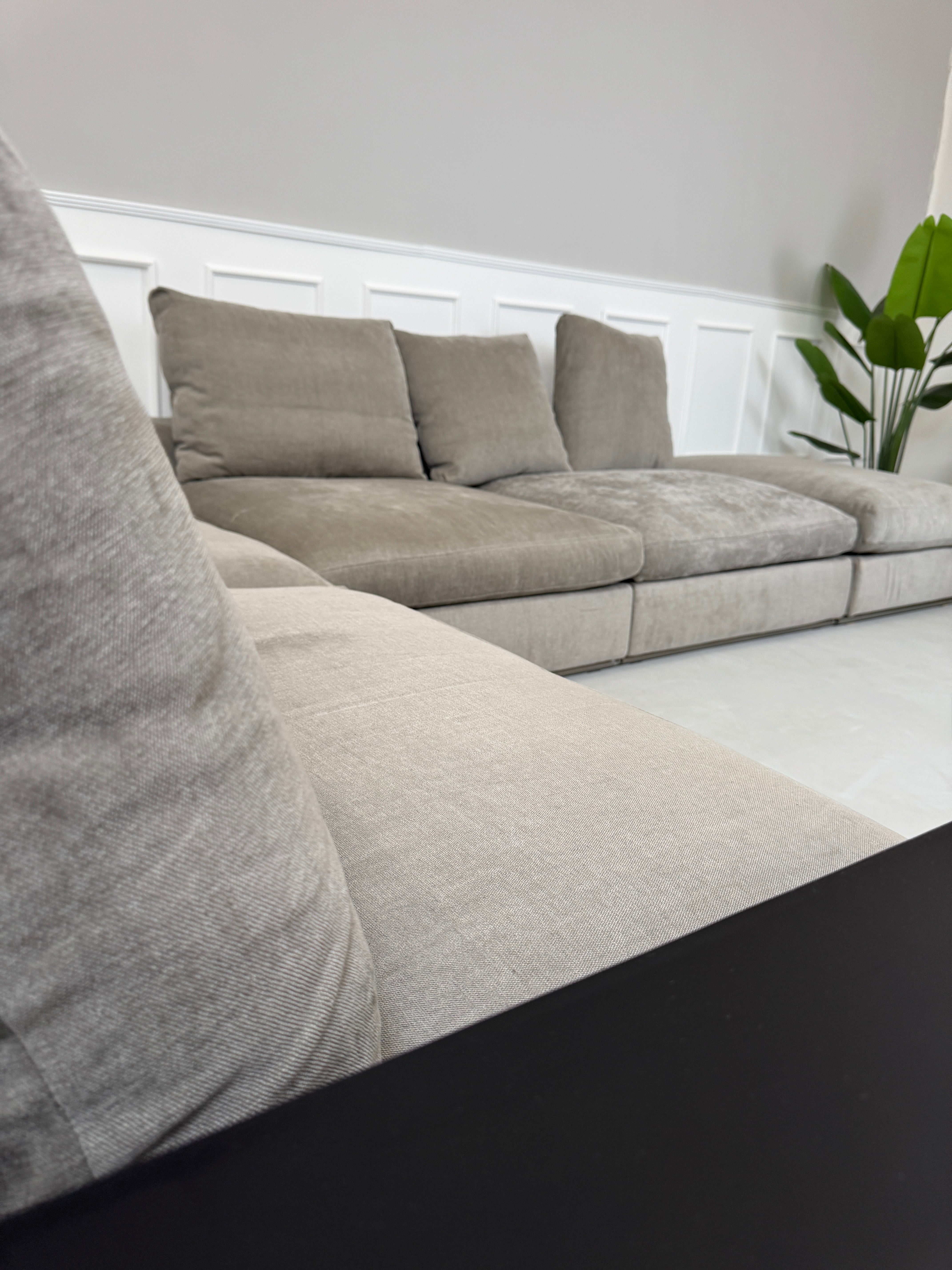 Gebrauchtes graues Flexform Groundpiece Designer Stoff Sofa vor einer Wand, stilvoll und modern eingerichtet.