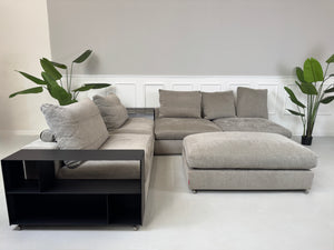 Gebrauchtes graues Flexform Groundpiece Designer Stoff Sofa vor einer Wand, stilvoll und modern eingerichtet.