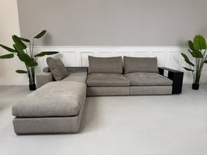 Gebrauchtes graues Flexform Groundpiece Designer Stoff Sofa vor einer Wand, stilvoll und modern eingerichtet.