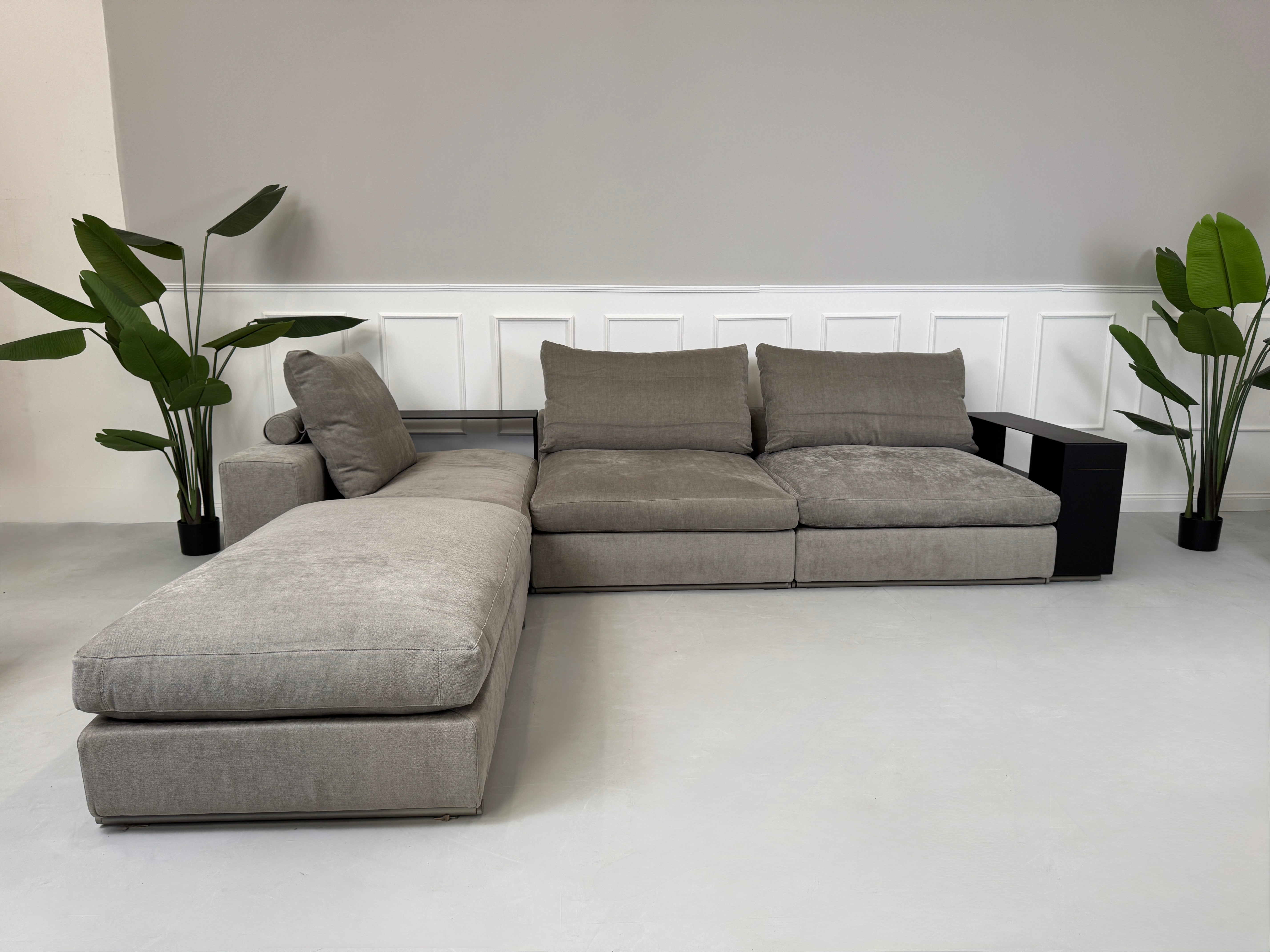 Gebrauchtes graues Flexform Groundpiece Designer Stoff Sofa vor einer Wand, stilvoll und modern eingerichtet.