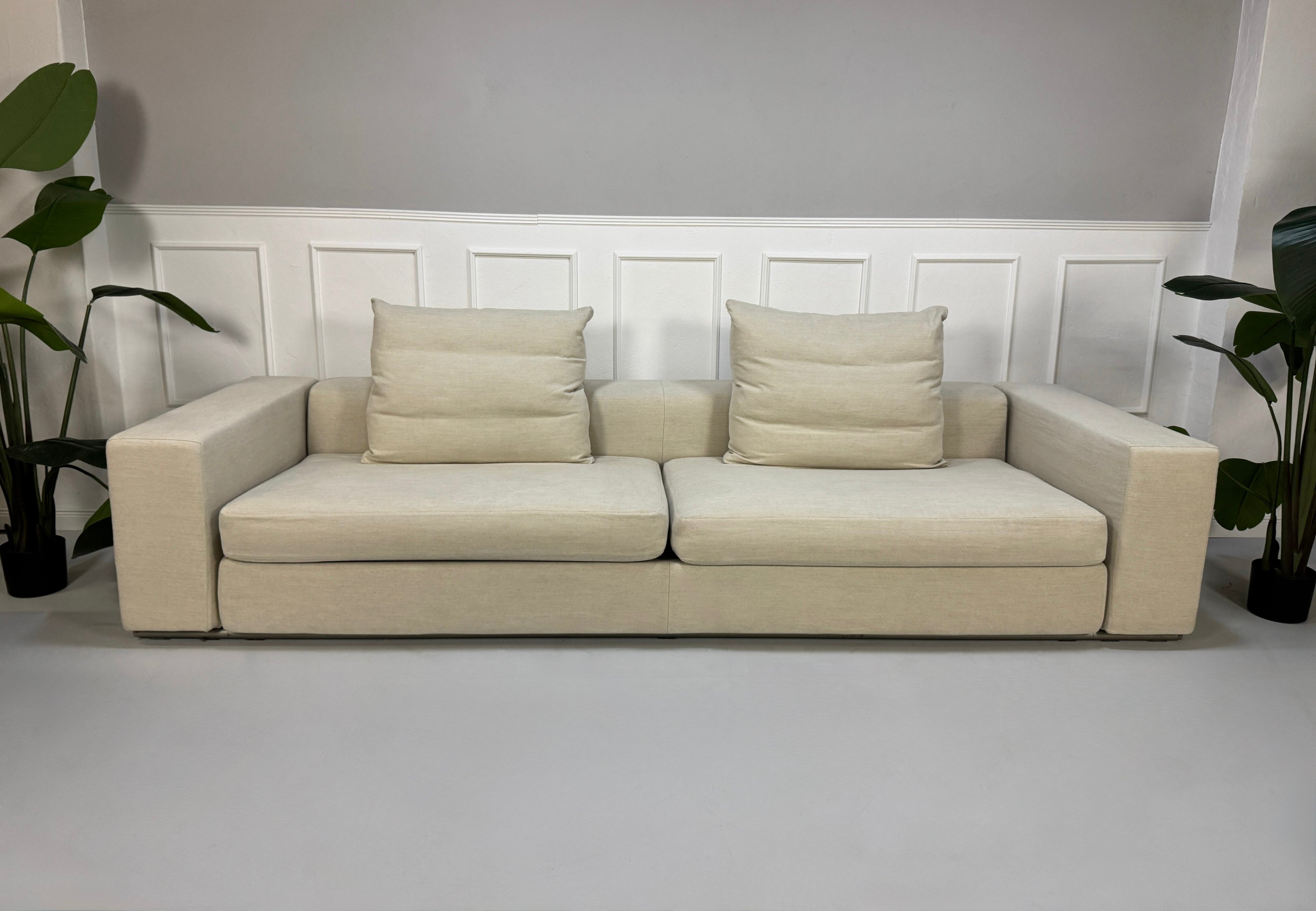 Gebrauchtes beiges Flexform Groundpiece Designer Stoff Sofa vor einer Wand, stilvoll und modern eingerichtet.