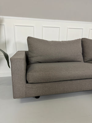 Gebrauchtes Flexform Magnum Stoff Sofa in der Farbe Taupe mit einem Hocker vor einer Wand, stilvoll und modern eingerichtet.