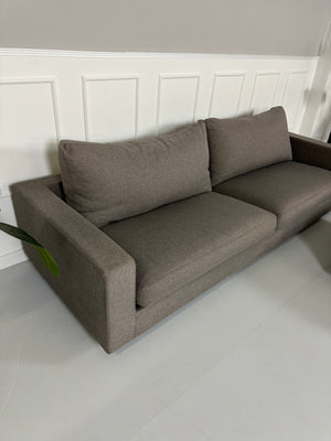 Gebrauchtes Flexform Magnum Stoff Sofa in der Farbe Taupe mit einem Hocker vor einer Wand, stilvoll und modern eingerichtet.