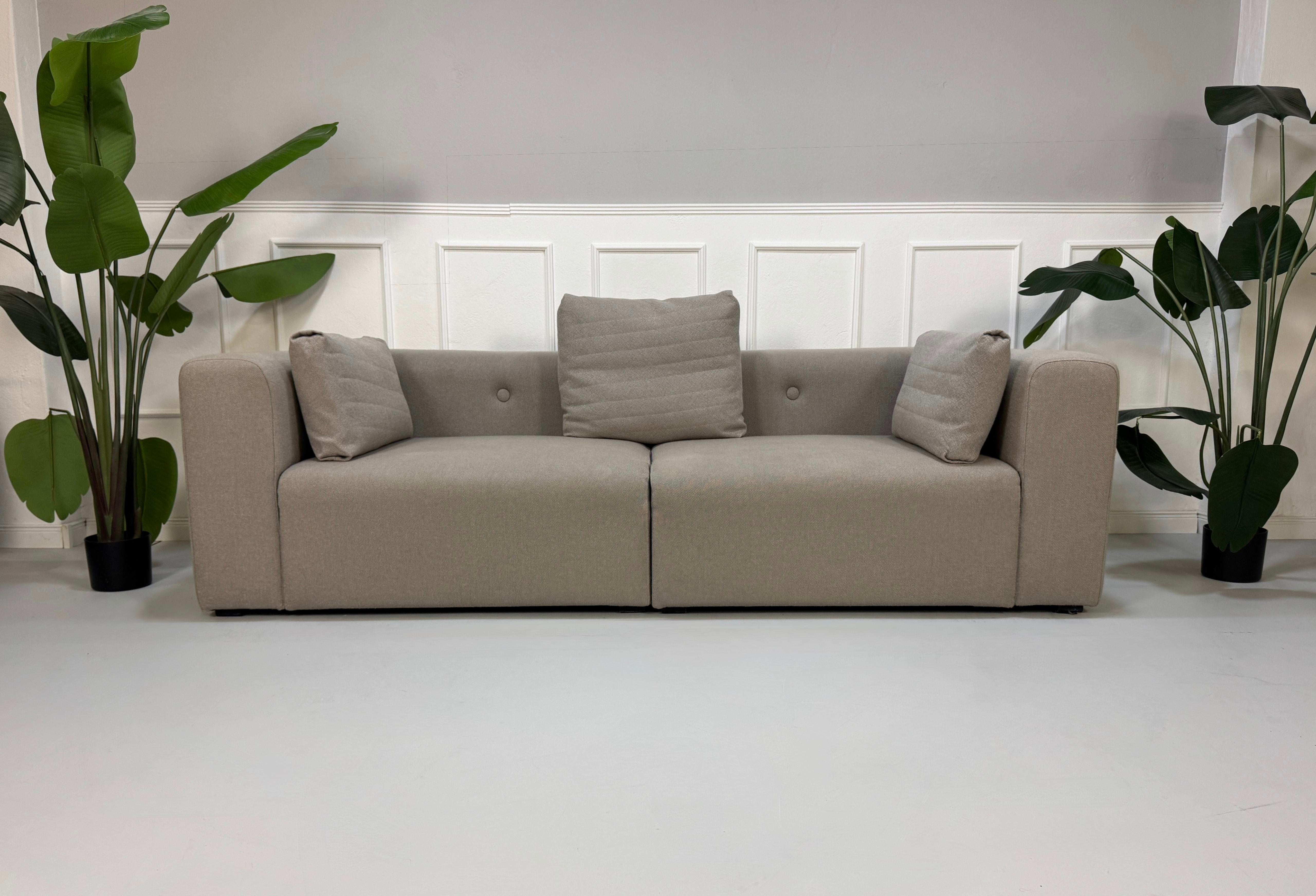 Gebrauchtes graues HAY Mags Designer Stoff Sofa vor einer Wand, stilvoll und modern eingerichtet.
