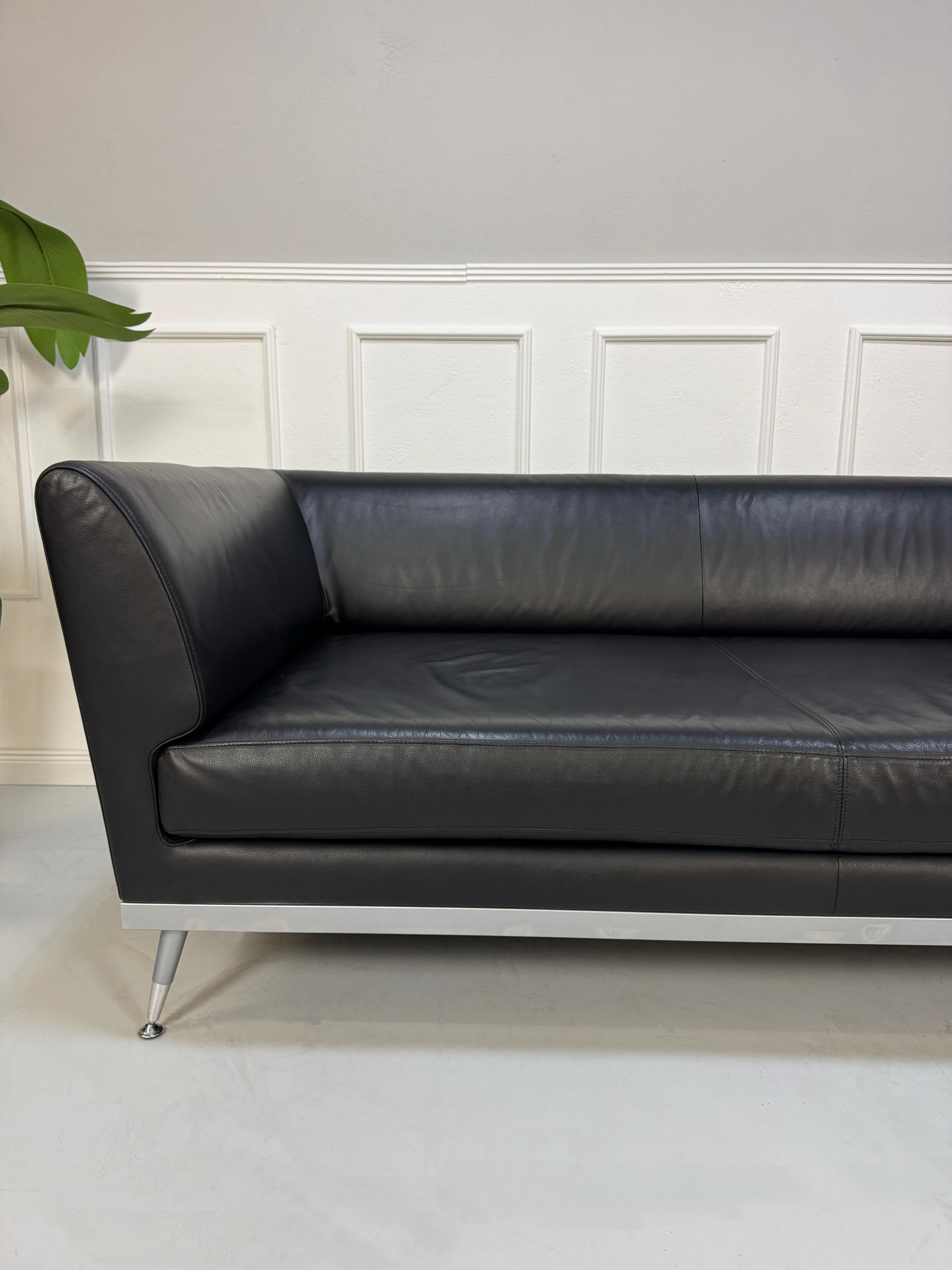 Gebrauchtes schwarzes Ligne Roset Fugue Designer Leder Sofa vor einer Wand, stilvoll und modern eingerichtet.