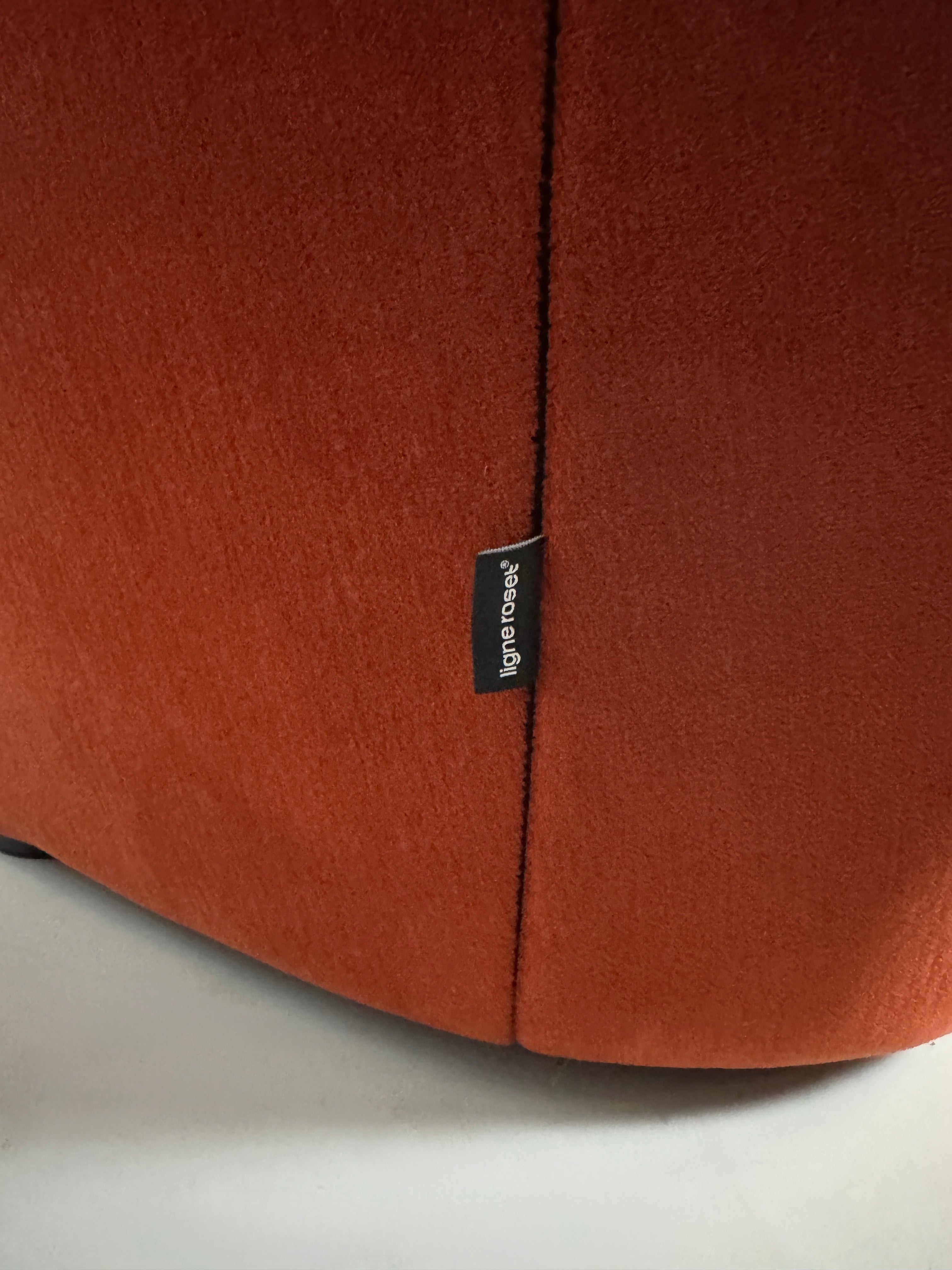Ligne Roset Ploum in der Farbe Orange Designer Stoff Sofa vor einer Wand, stilvoll und modern eingerichtet.
