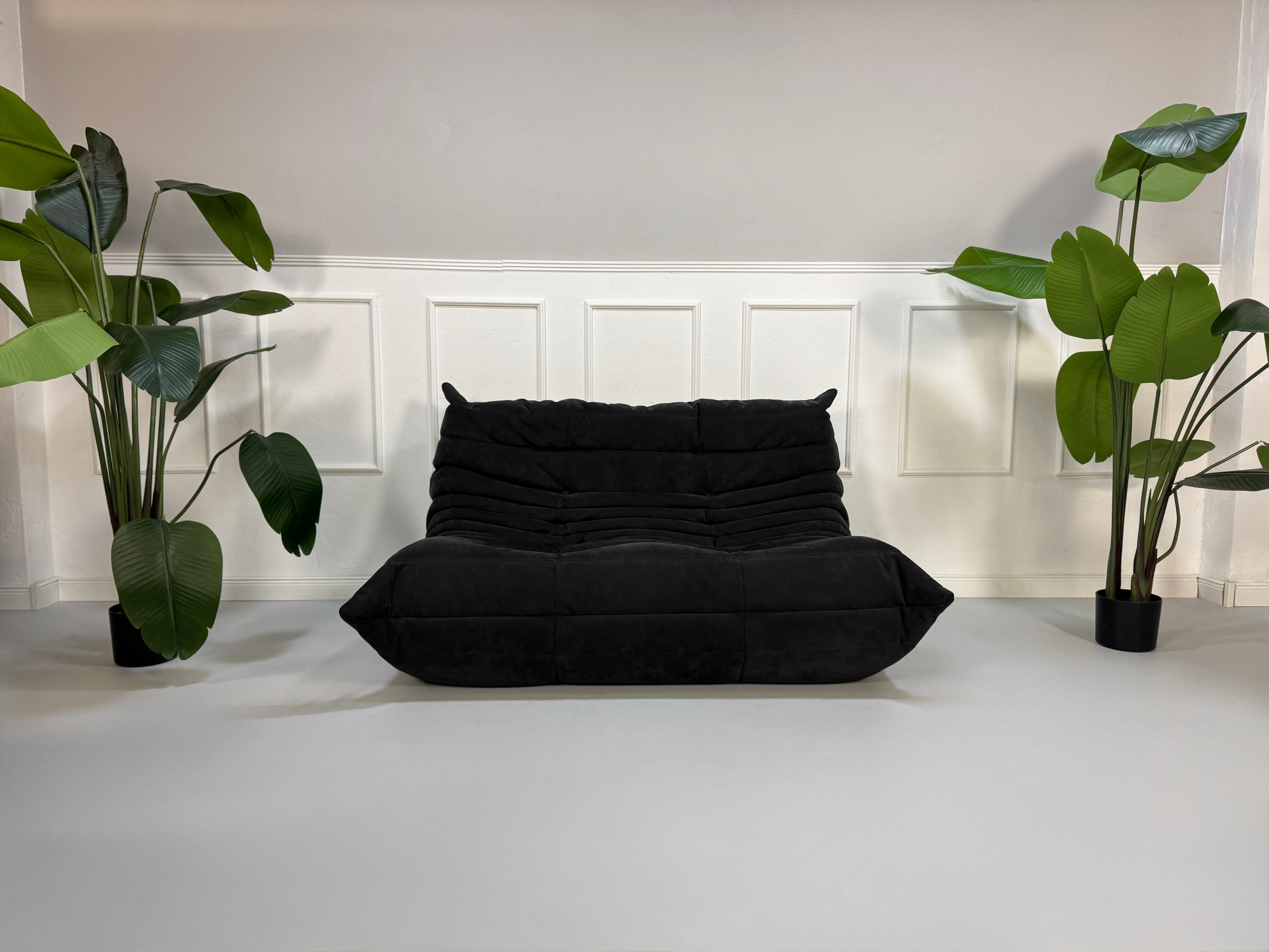 Gebrauchtes graues Ligne Roset Togo Designer Stoff Sofa vor einer Wand, stilvoll und modern eingerichtet.
