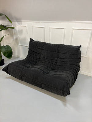 Gebrauchtes graues Ligne Roset Togo Designer Stoff Sofa vor einer Wand, stilvoll und modern eingerichtet.